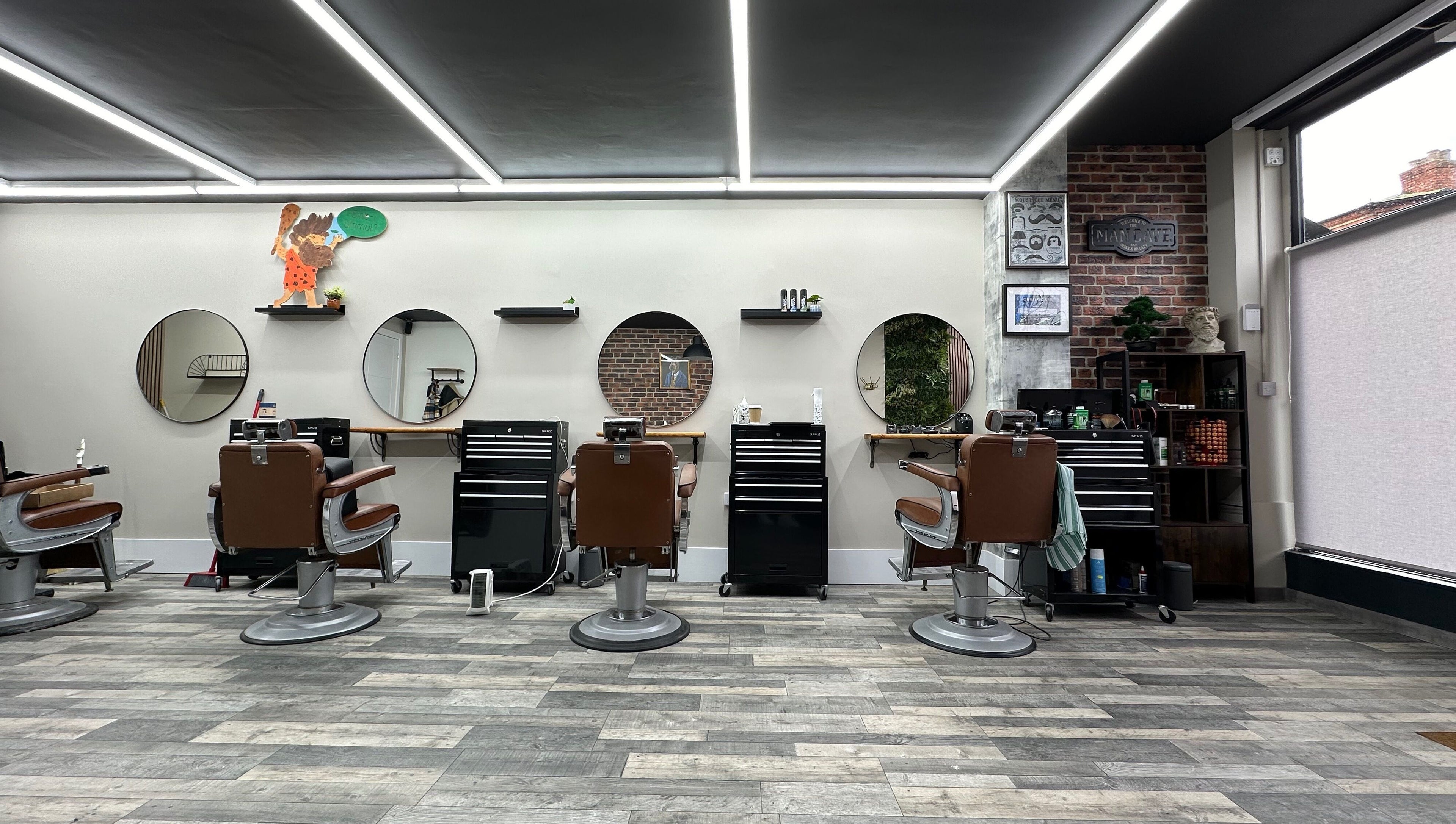 Modern interior of The Man Cave Barbershop, Northampton, England, GB with sleek barber chairs and mirrors.