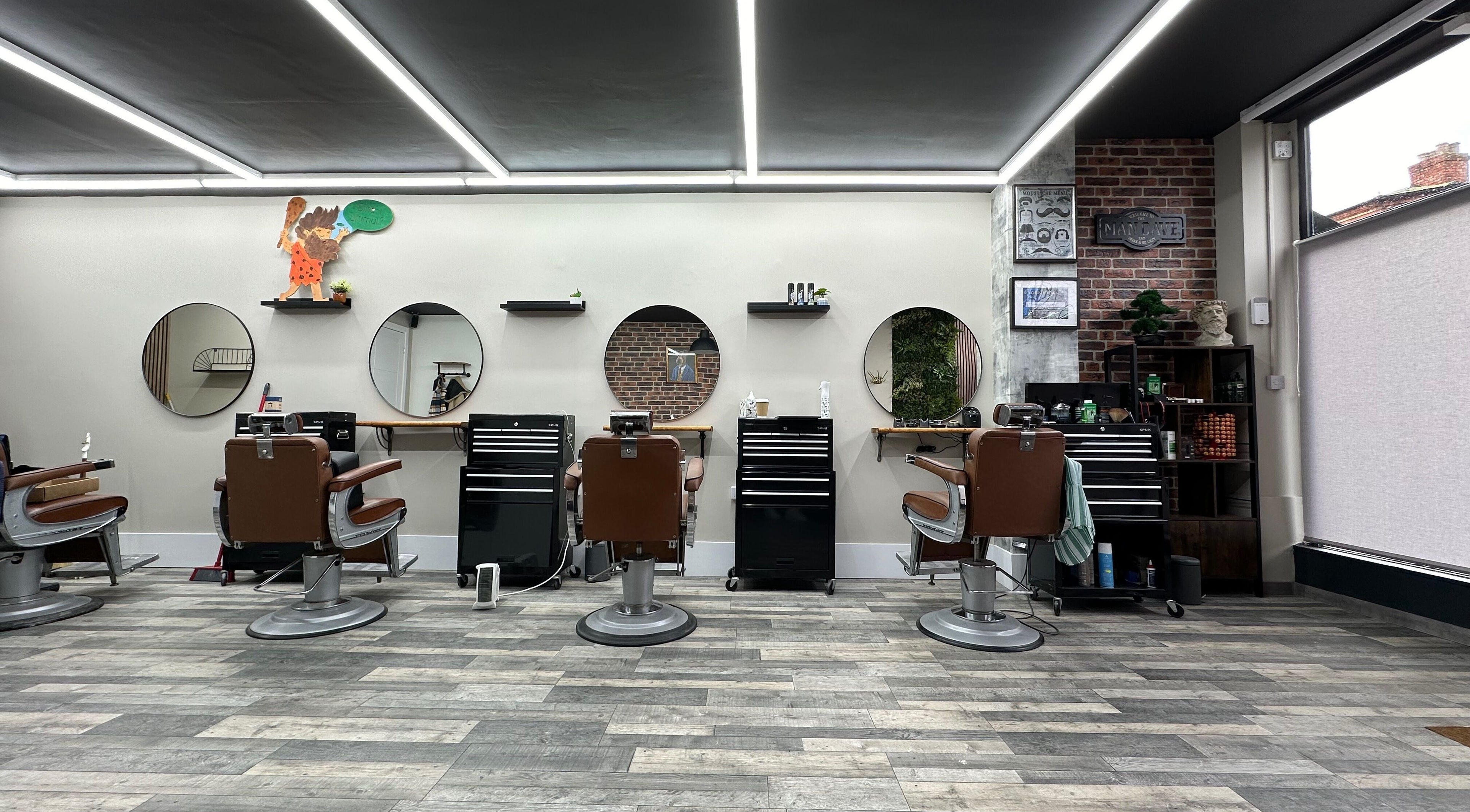Modern interior of The Man Cave Barbershop, Northampton, England, GB with sleek barber chairs and mirrors.