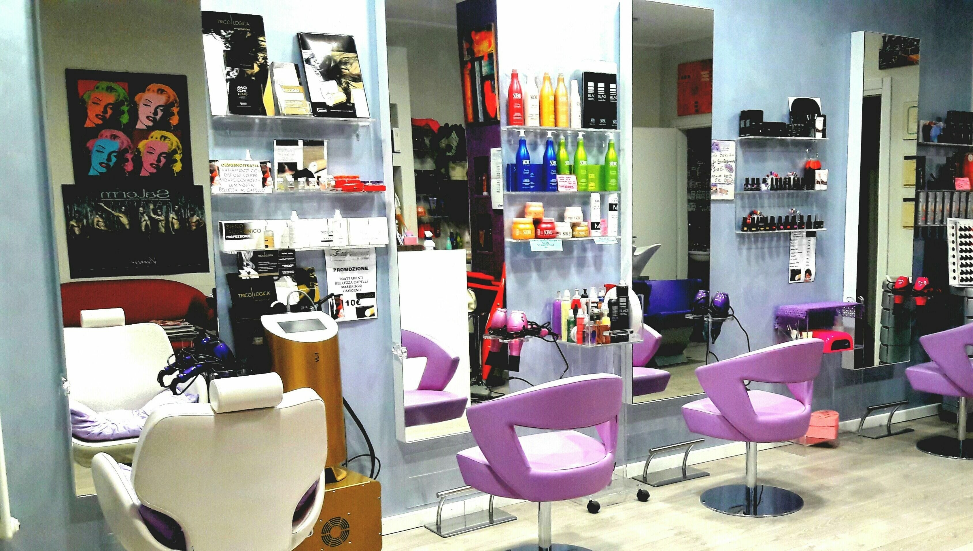 Interno di Lady Glamour parrucchieri a Senago, Lombardia, IT: accoglienti sedie viola e prodotti di bellezza sugli scaffali.