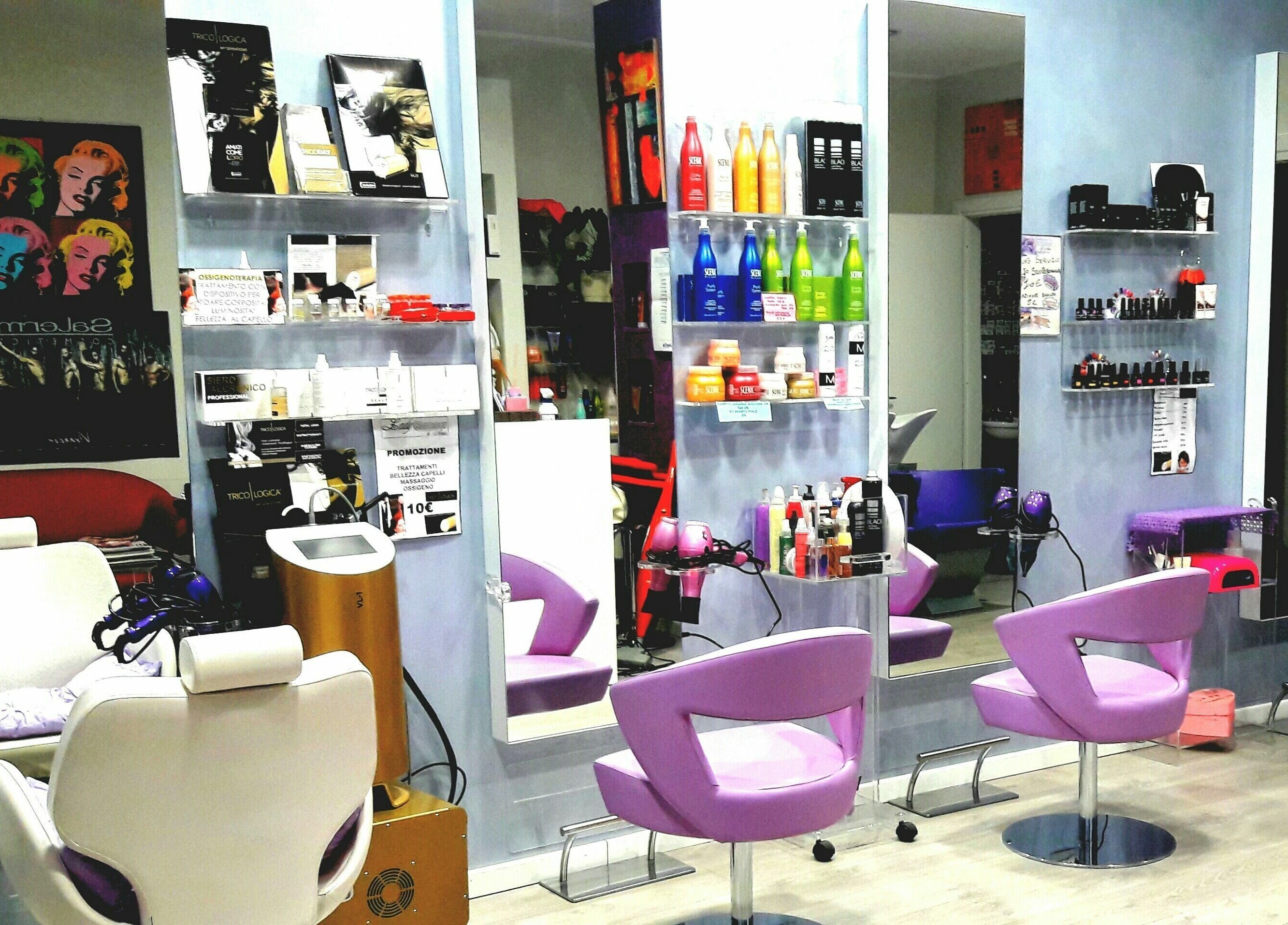 Interno di Lady Glamour parrucchieri a Senago, Lombardia, IT: accoglienti sedie viola e prodotti di bellezza sugli scaffali.