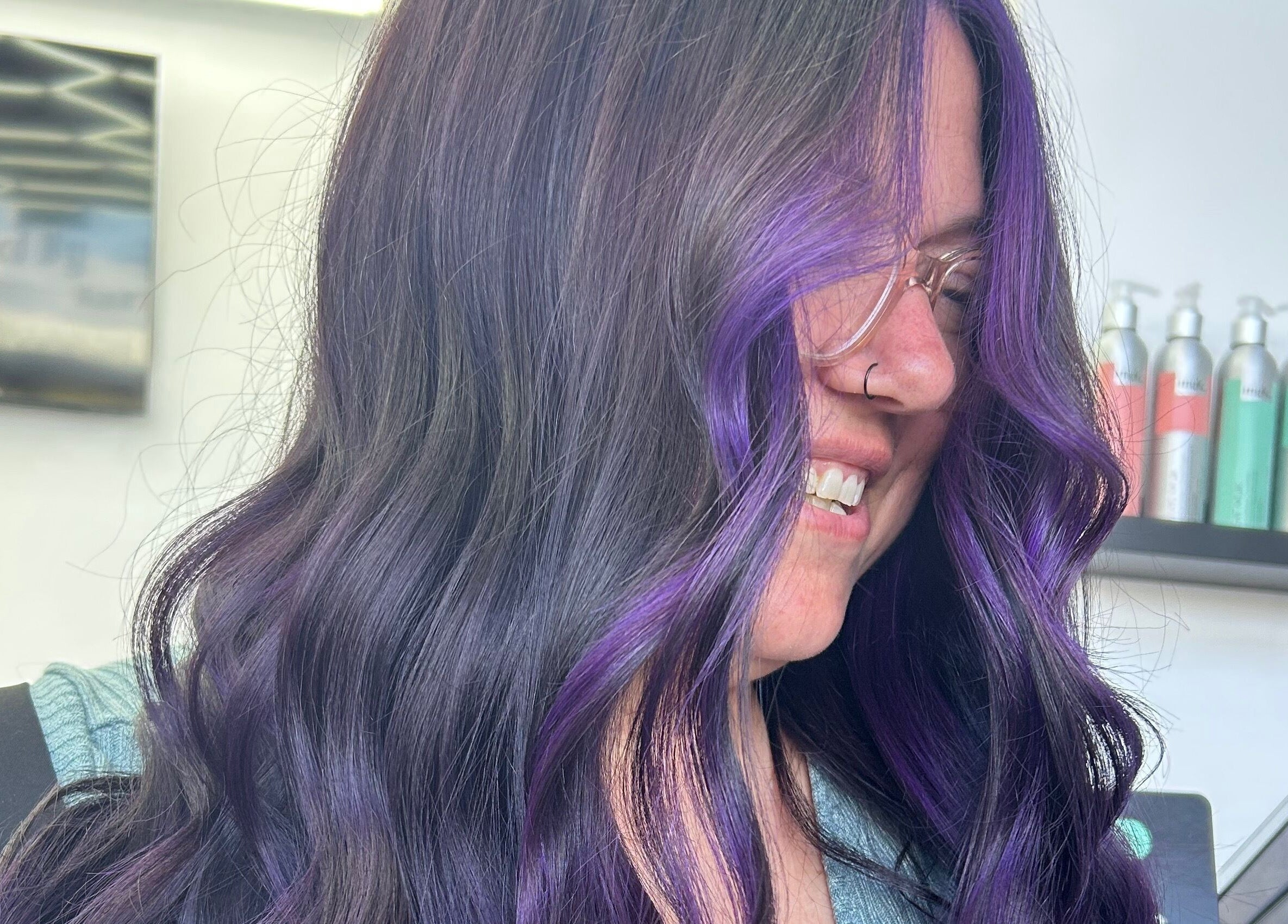 Woman with vibrant purple highlights at Blond by Jade in Willaston, South Australia, AU, smiling in salon.