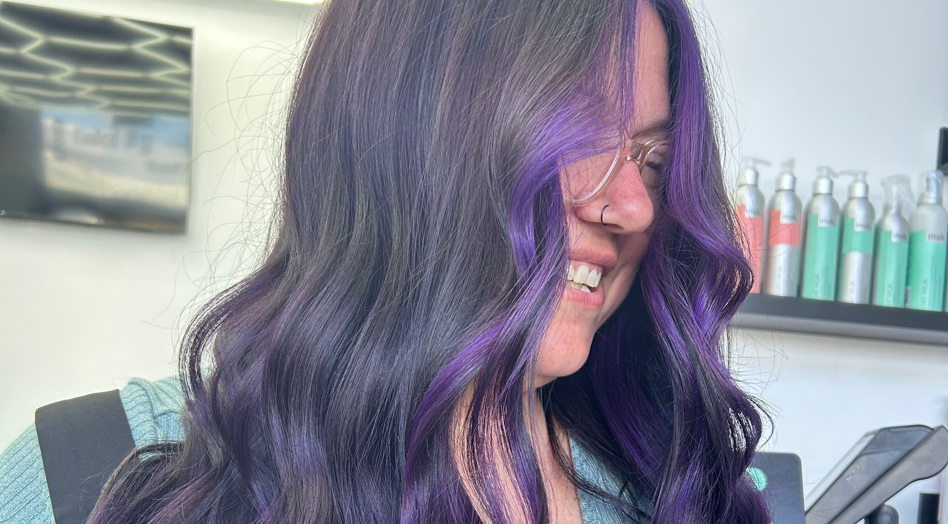 Woman with vibrant purple highlights at Blond by Jade in Willaston, South Australia, AU, smiling in salon.