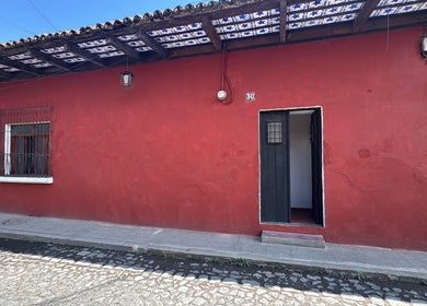 Fachada exterior de Original Hair Studio en Antigua Guatemala, Sacatepéquez, GT, con paredes rojas y puerta abierta.