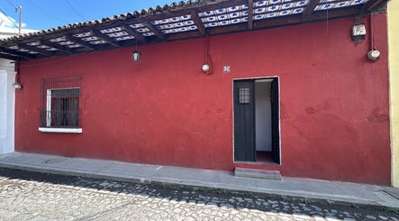 Fachada exterior de Original Hair Studio en Antigua Guatemala, Sacatepéquez, GT, con paredes rojas y puerta abierta.