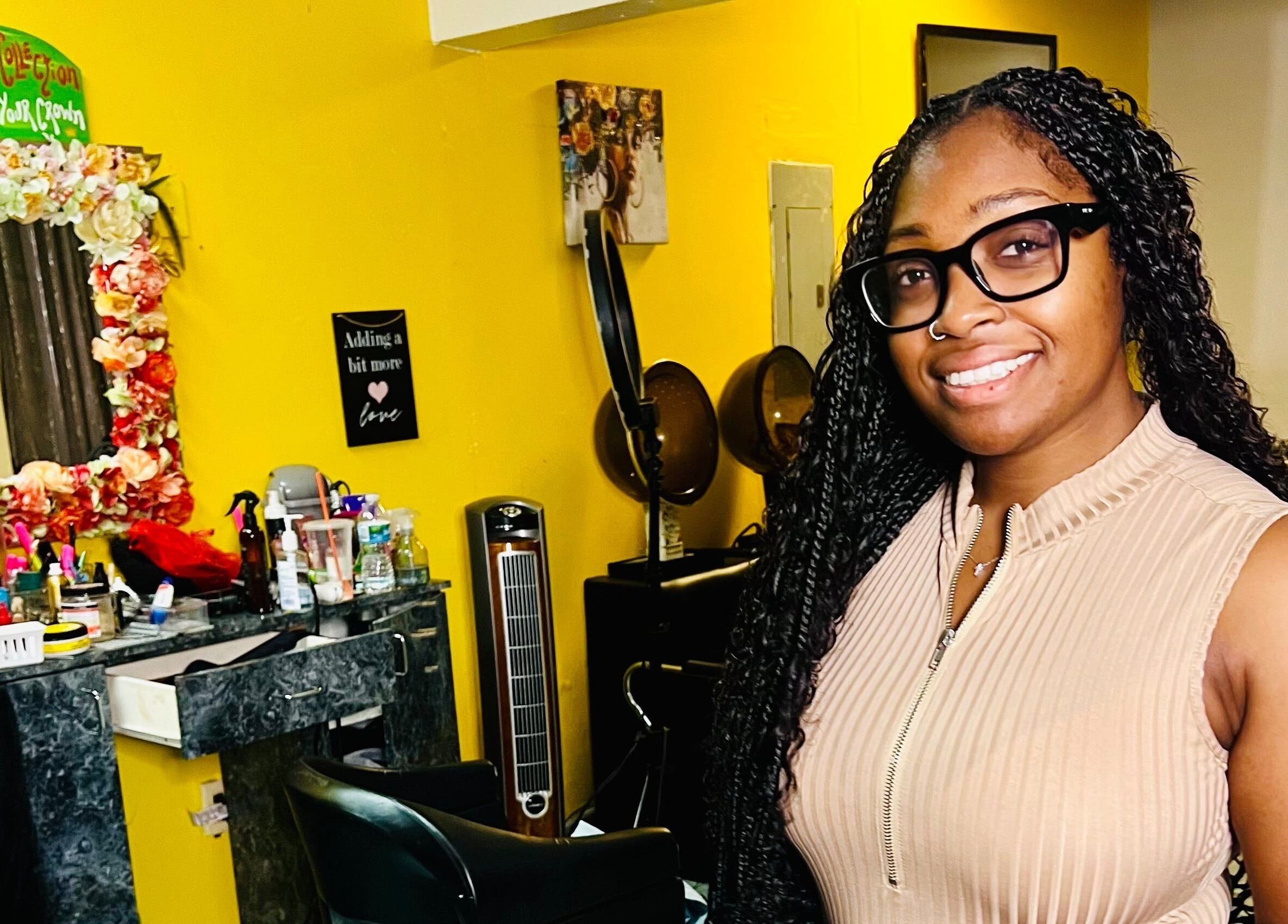 Smiling professional in Goldy Mane Collection salon, Miami, Florida, US. Vibrant decor in the background.
