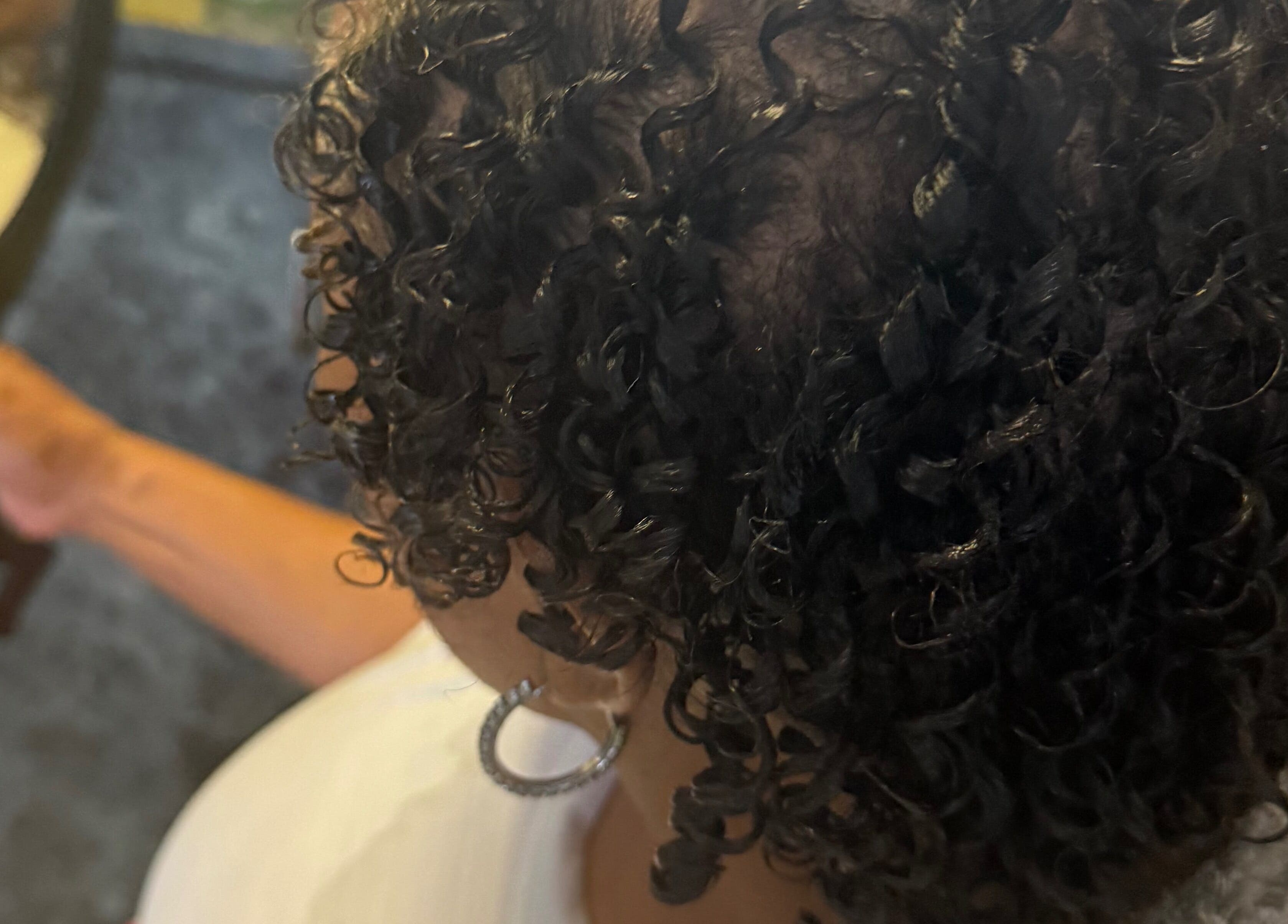 Lush curly hairstyle at Goldy Mane Collection, Miami, Florida, US, highlighted in a mirror view.