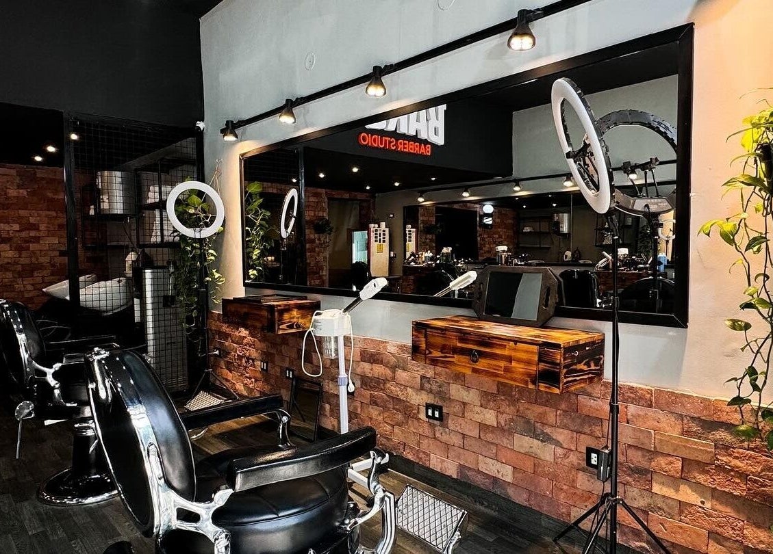 Interior elegante de Bargo Barber Studio en Lince, Provincia De Lima, PE, con sillas de barbería y espejos iluminados.