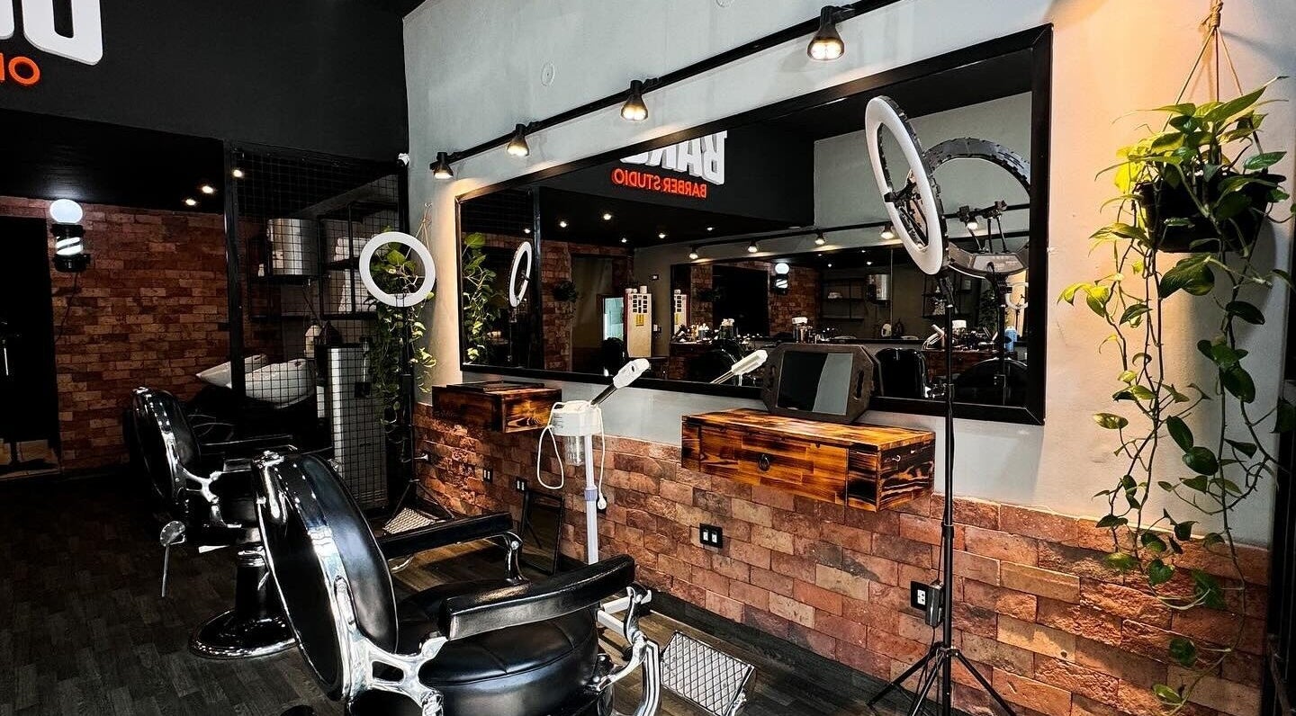 Interior elegante de Bargo Barber Studio en Lince, Provincia De Lima, PE, con sillas de barbería y espejos iluminados.