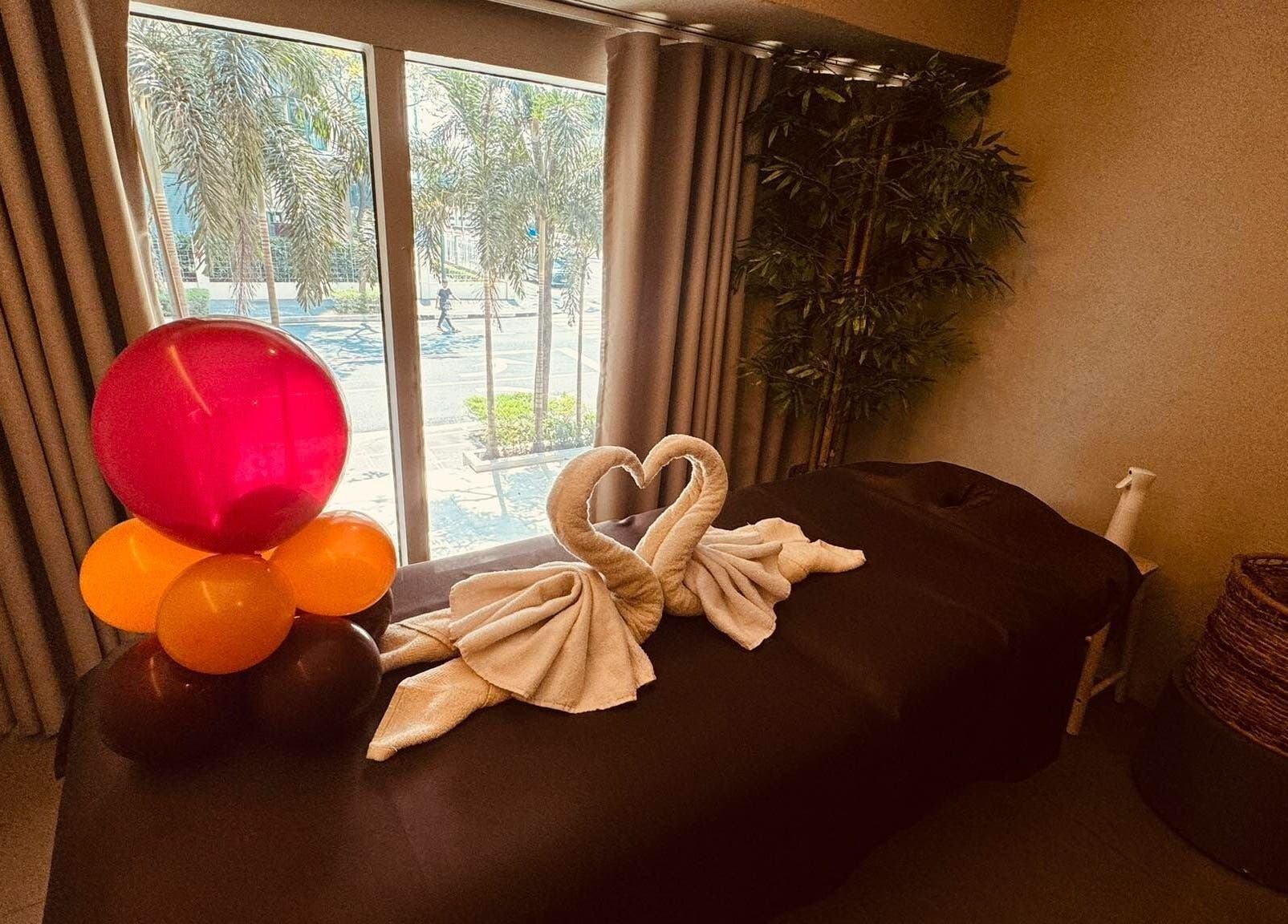 Relaxing massage room at Bamboo Spa Beauty and Wellness BGC, Taguig, Metro Manila, PH with towel swans and balloons.