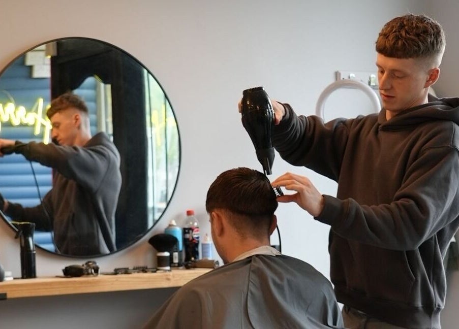 Barber expertly styling a haircut at Harry’s Barbershop, Ramsbottom, England, GB.