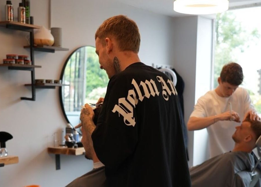 Barbers styling clients at Harry’s Barbershop, Ramsbottom, England, GB. Quality grooming in a modern setting.