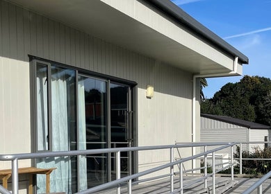 Exterior view of Body and Soul Holistic Wellbeing in Mokau, Waikato, NZ with inviting deck and lush greenery.
