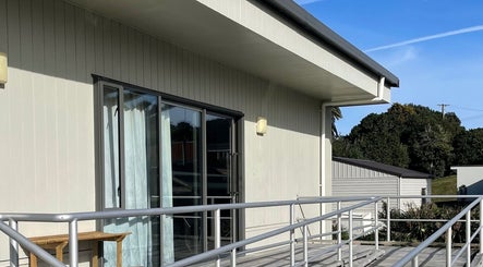 Exterior view of Body and Soul Holistic Wellbeing in Mokau, Waikato, NZ with inviting deck and lush greenery.