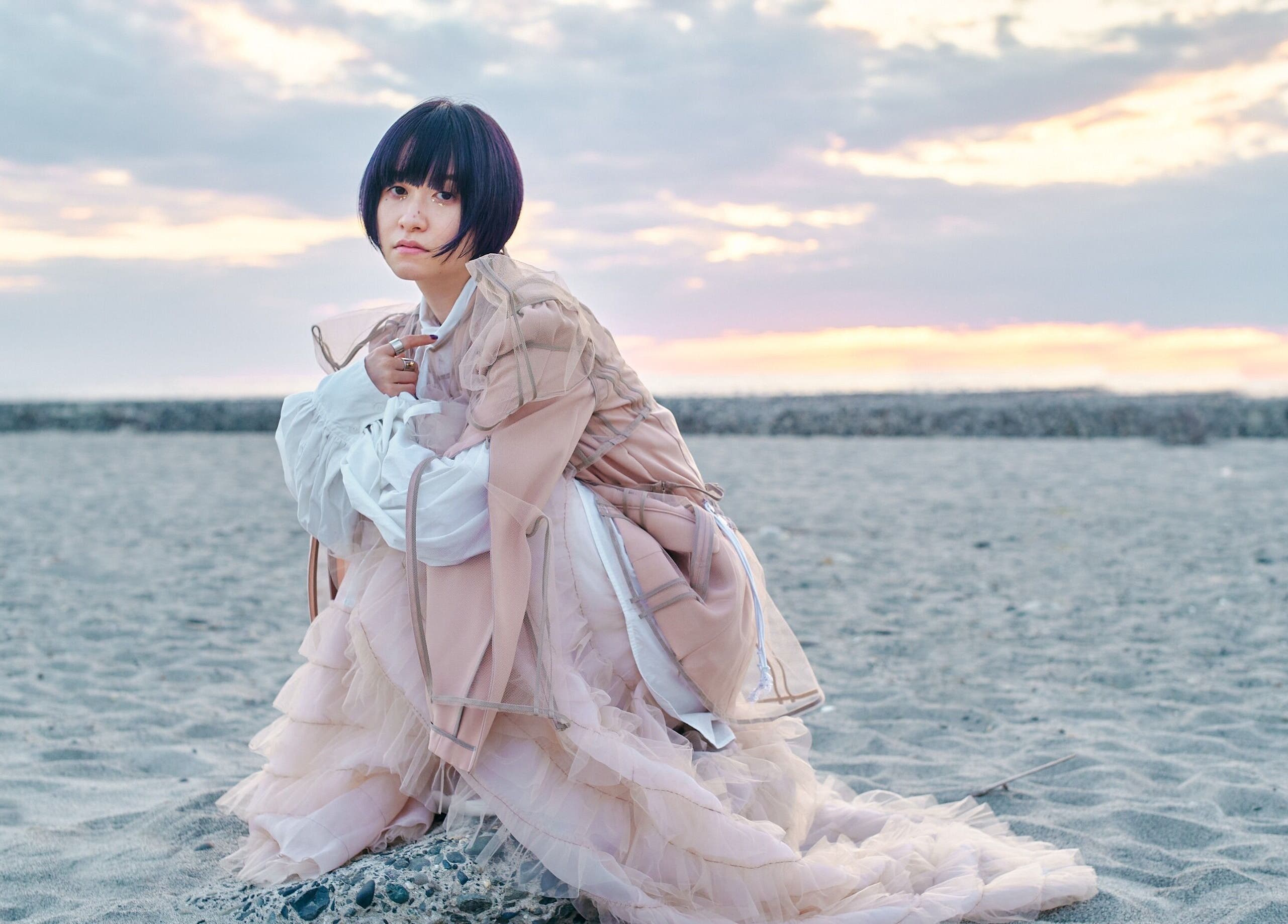 A person in elegant attire on a beach at AL etro in กรุงเทพมหานคร, กรุงเทพมหานคร, TH during sunset.