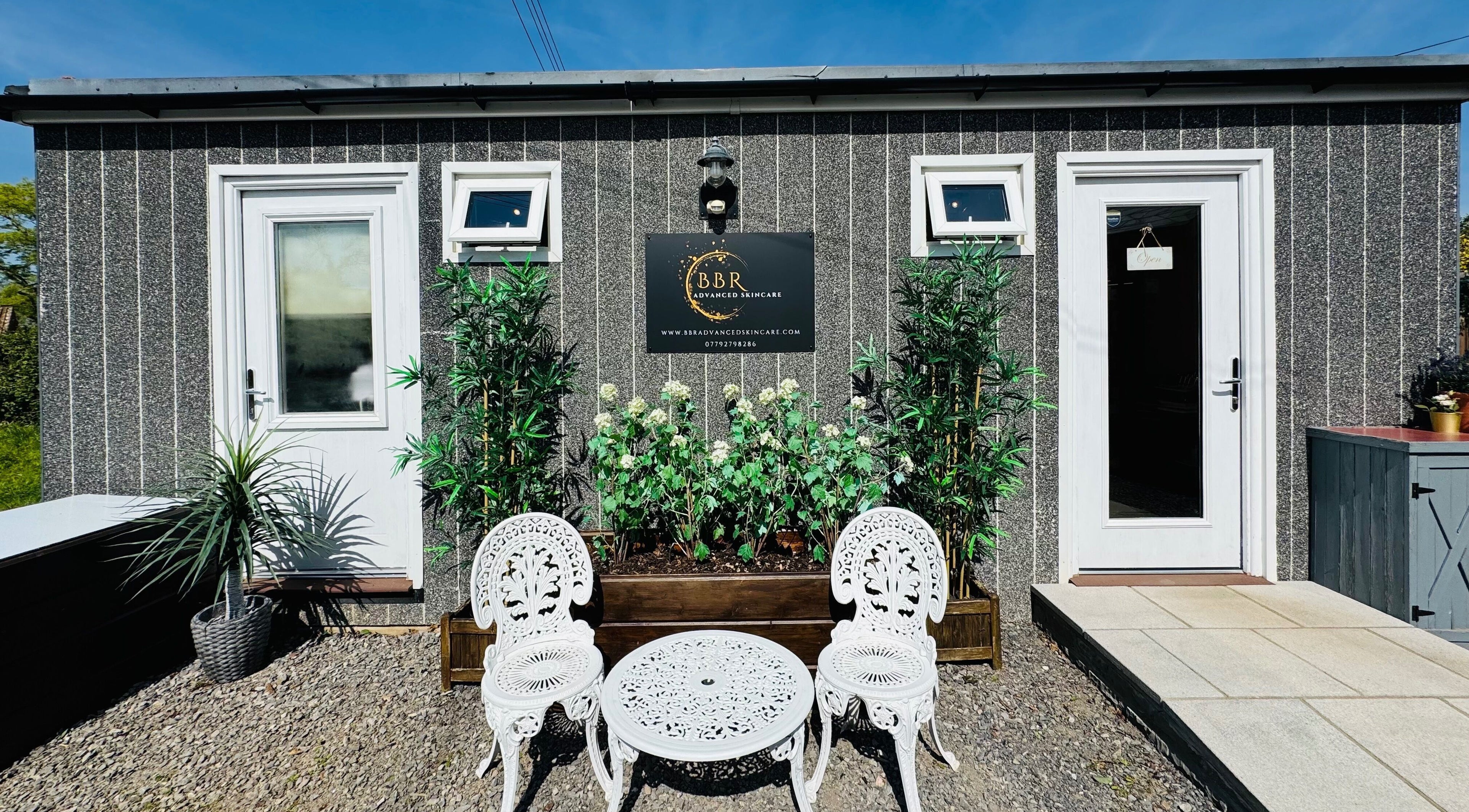 Front exterior view of BBR Advanced Skincare in Wells, England with seating and lush plants.