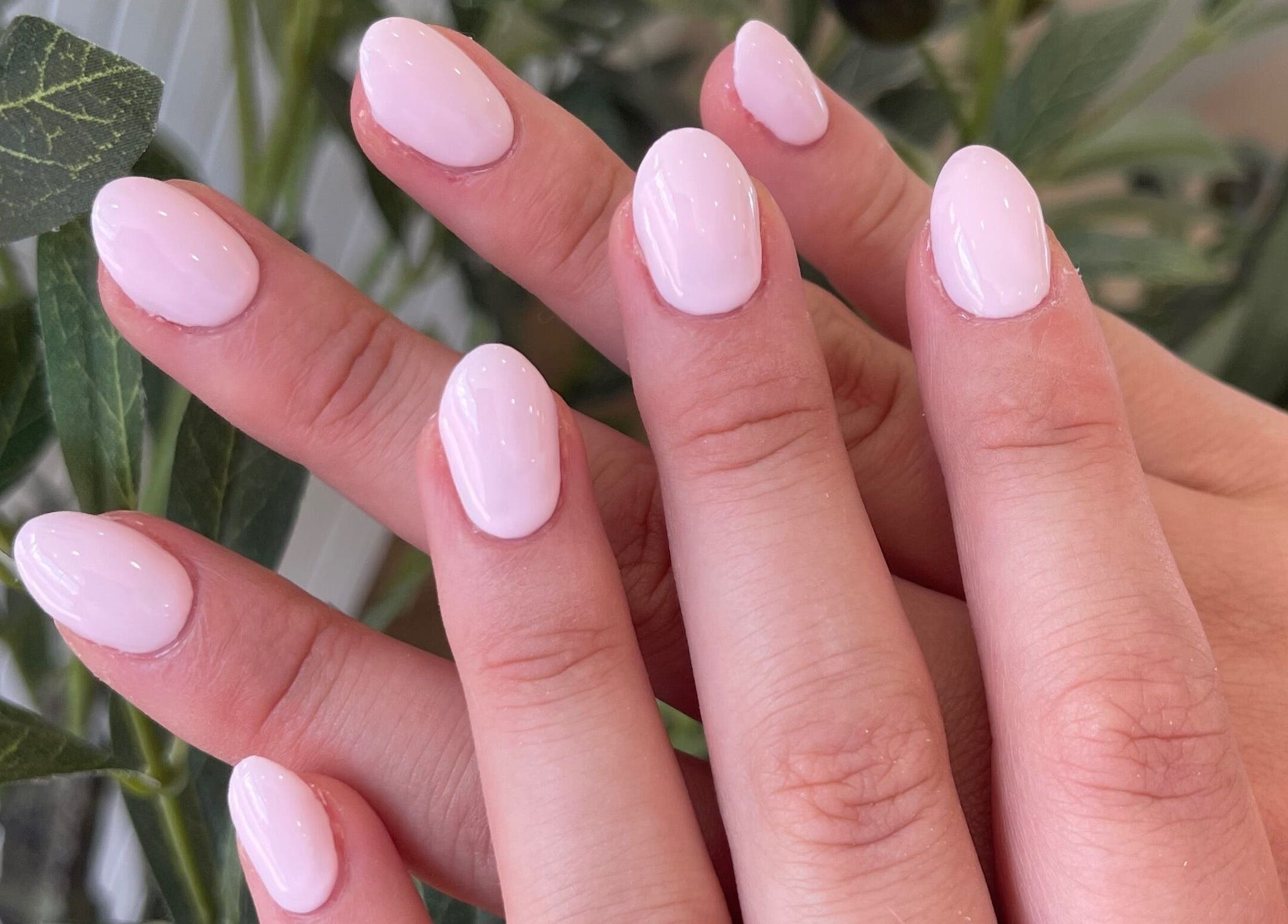 Elegant pink manicure at The NailpodTw in Royal Tunbridge Wells, England, GB with lush plant background.