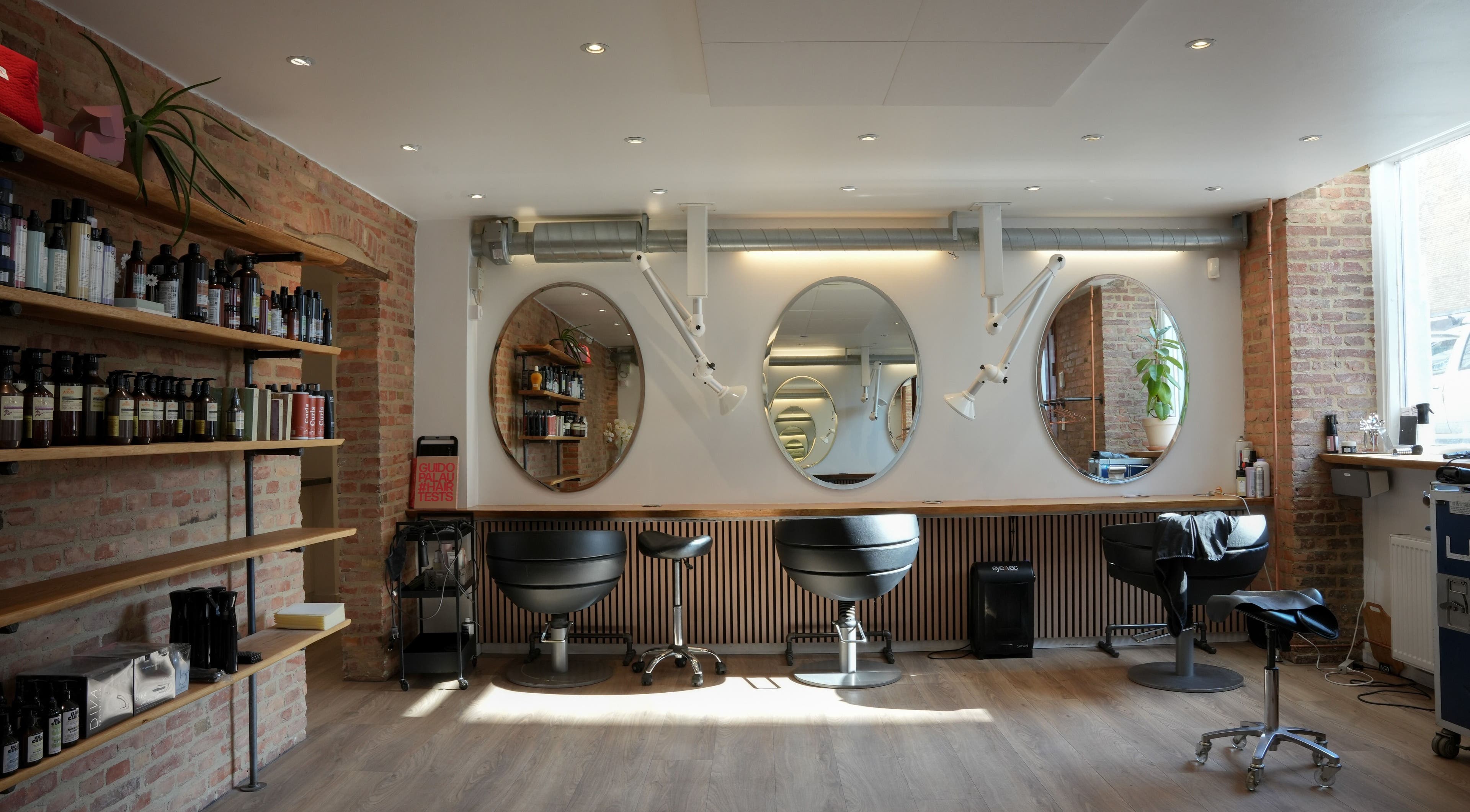 Inside view of Hair By Penny Kotsi salon in København, Denmark, DK showcasing stylish chairs and mirrors.