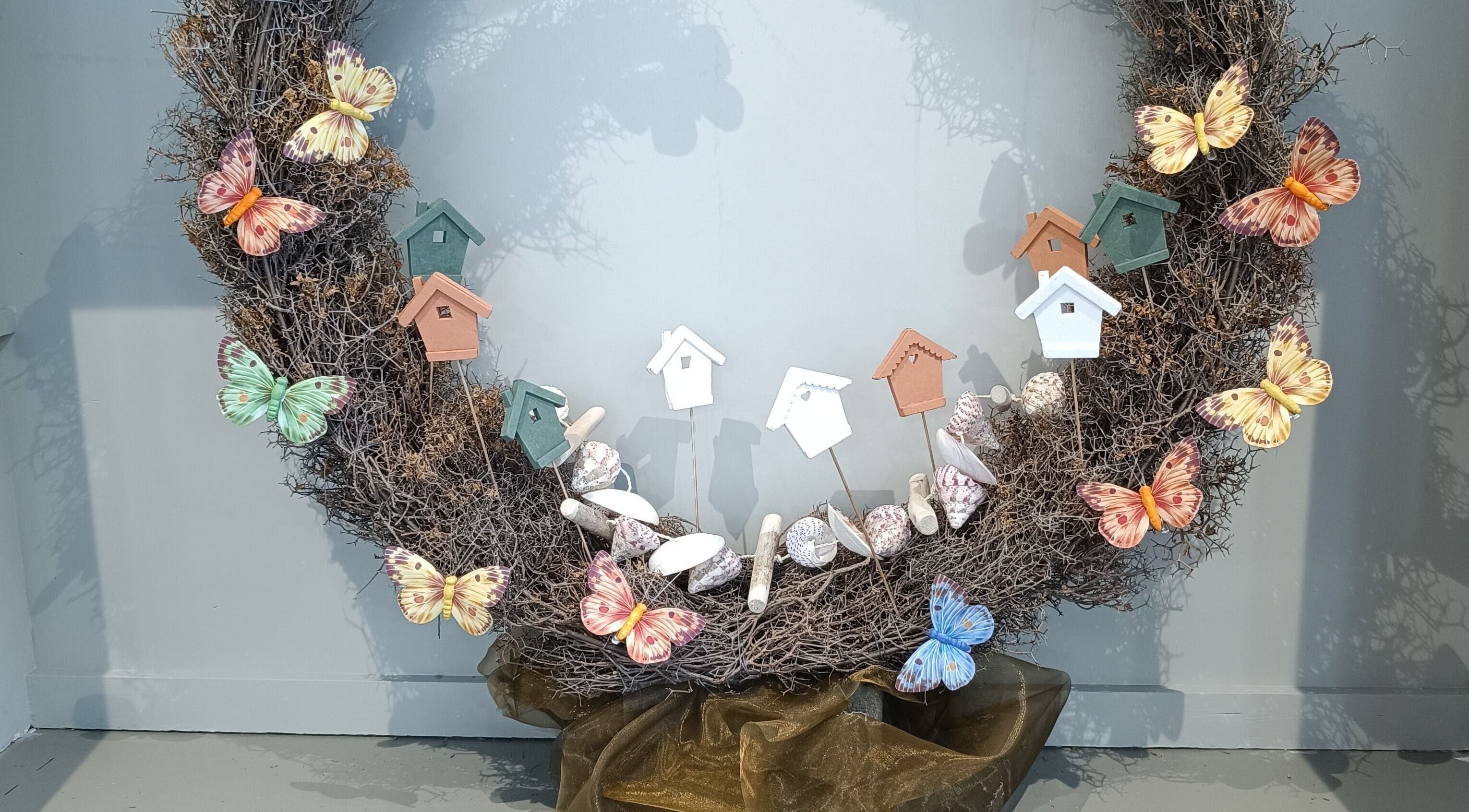 Decoratieve krans met kleurrijke vlinders en vogelhuisjes bij Haar&Zo Brugge, Brugge, Vlaams Gewest, BE.