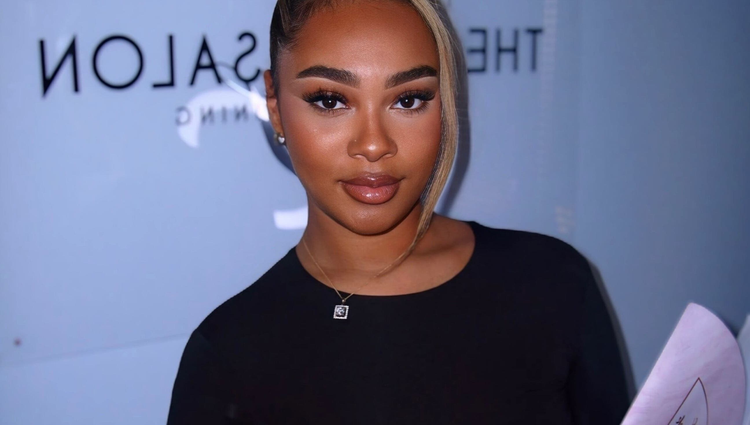 Smiling woman at Aaliyahlashh in Crawley, England, GB, holding a document.