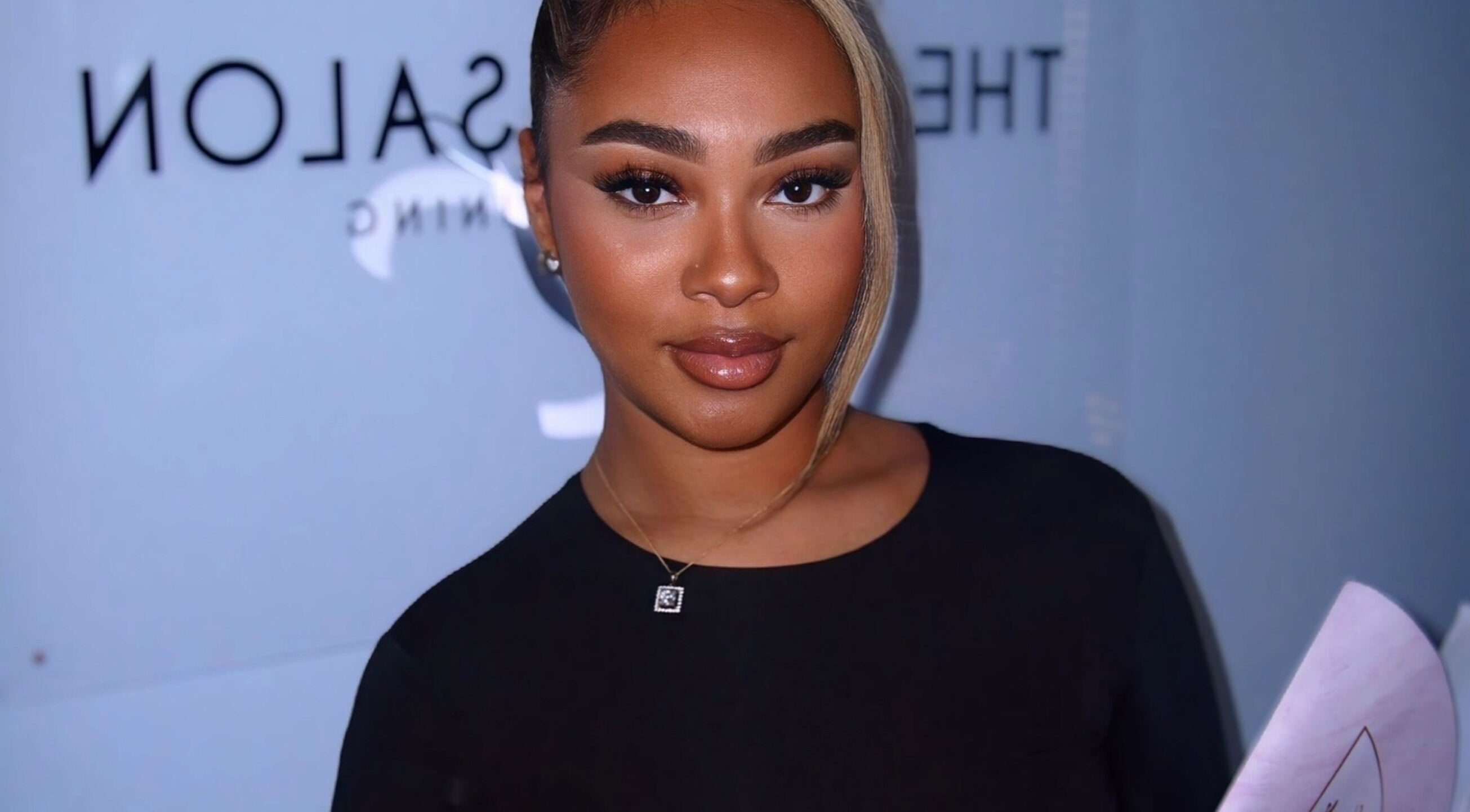 Smiling woman at Aaliyahlashh in Crawley, England, GB, holding a document.