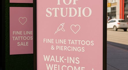 Elegant pink sign of Top Studio Tattoo & Piercing in Toronto, Ontario, CA welcoming walk-ins.