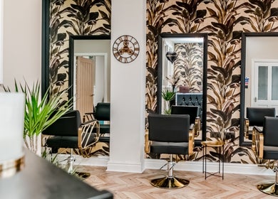 Elegant salon interior with tropical decor at The Hair Lounge, Chorley, England, GB. Modern black chairs and mirrors.