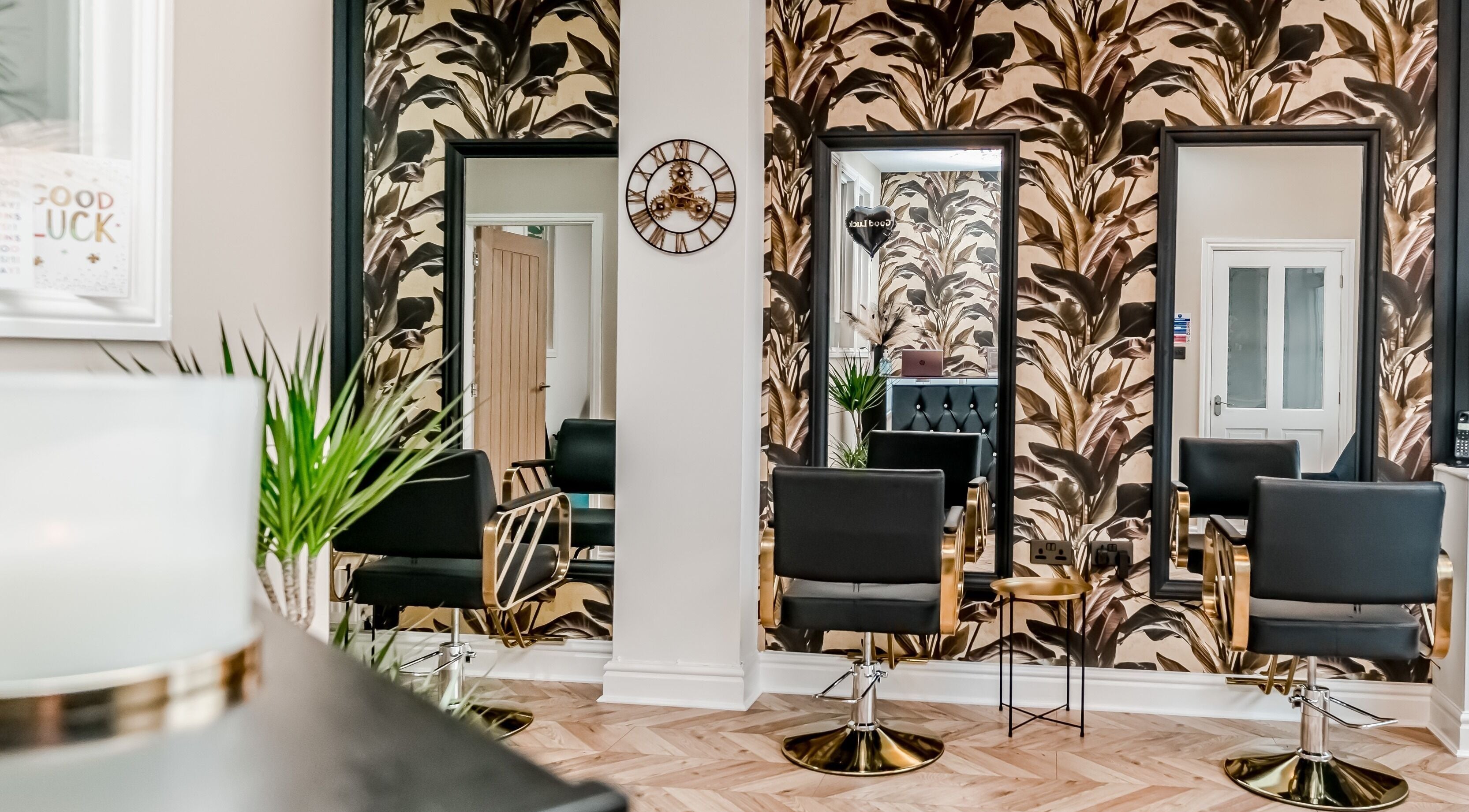Elegant salon interior with tropical decor at The Hair Lounge, Chorley, England, GB. Modern black chairs and mirrors.