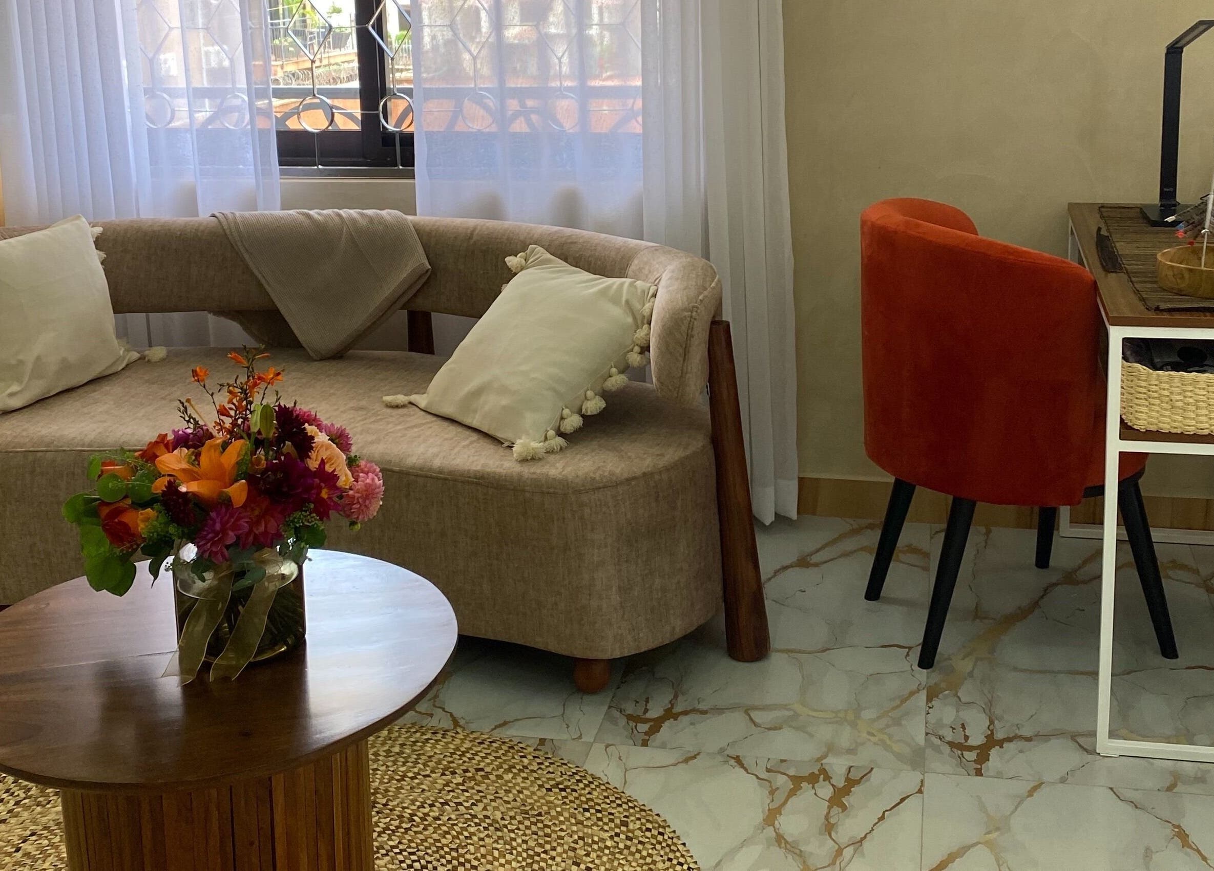 Elegant lounge at The Pod, Kampala, Central Region, UG, featuring a stylish couch and vibrant floral centerpiece.