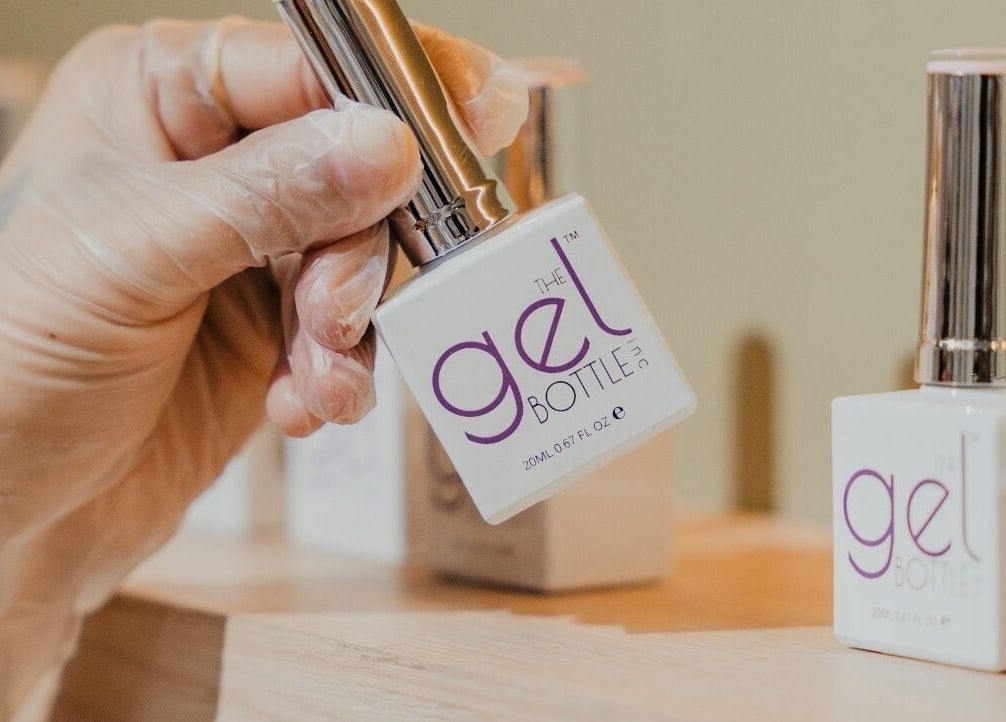 Hand holding gel nail polish at Peach Beauty Bar, Dubai, Dubai, AE, showcasing premium products.