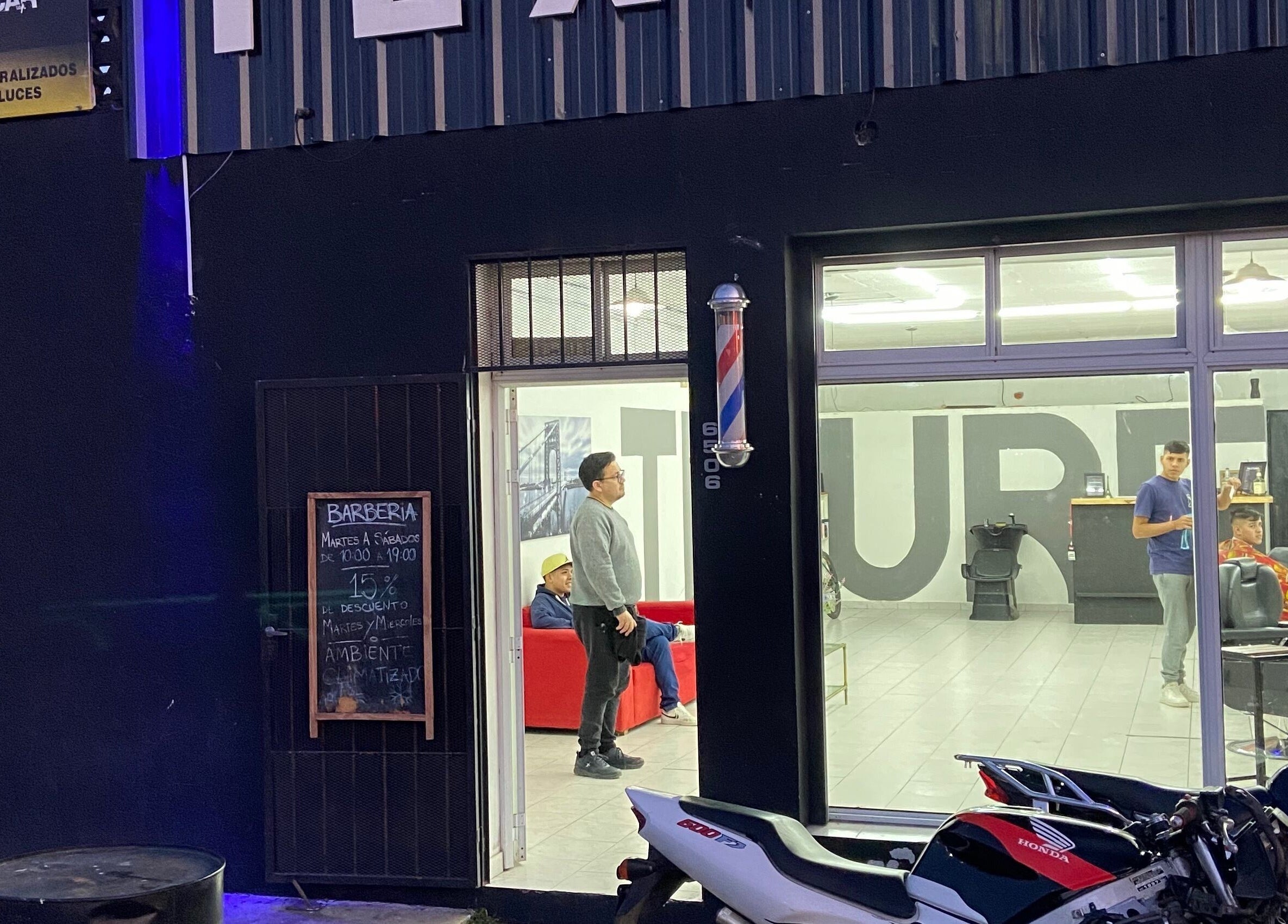 Fachada iluminada de Texture Barbershop en Rosario, Santa Fe, AR, mostrando actividad nocturna.