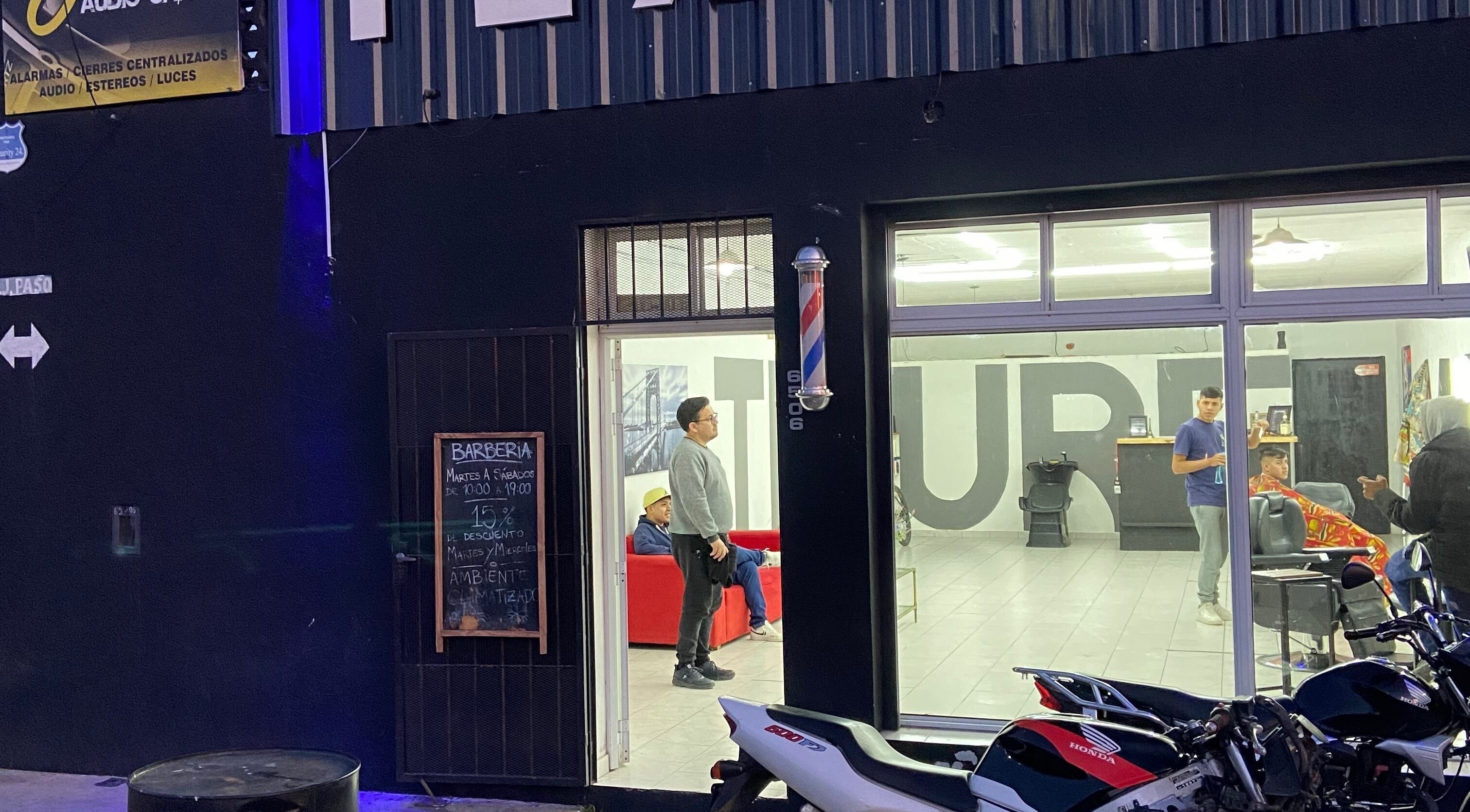 Fachada iluminada de Texture Barbershop en Rosario, Santa Fe, AR, mostrando actividad nocturna.