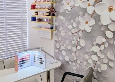 Cozy beauty corner at Amber Beauties, Goffs Oak, England, GB with floral wall and nail polish display.