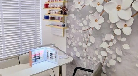 Cozy beauty corner at Amber Beauties, Goffs Oak, England, GB with floral wall and nail polish display.