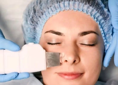 Facial treatment at Amber Beauties, Goffs Oak, England, GB. Hands in gloves applying a spa device to client's face.