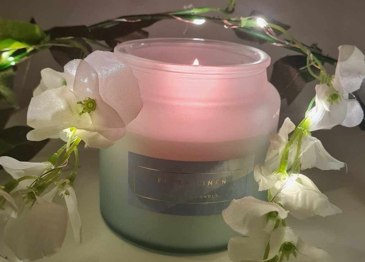 Lit scented candle with white flowers at Blissful Touch, Bugle, England, GB.