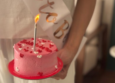 كعكة وردية صغيرة بحجم اليد مع شمعة مضاءة في أوليا سبا، الرياض، منطقة الرياض، السعودية.