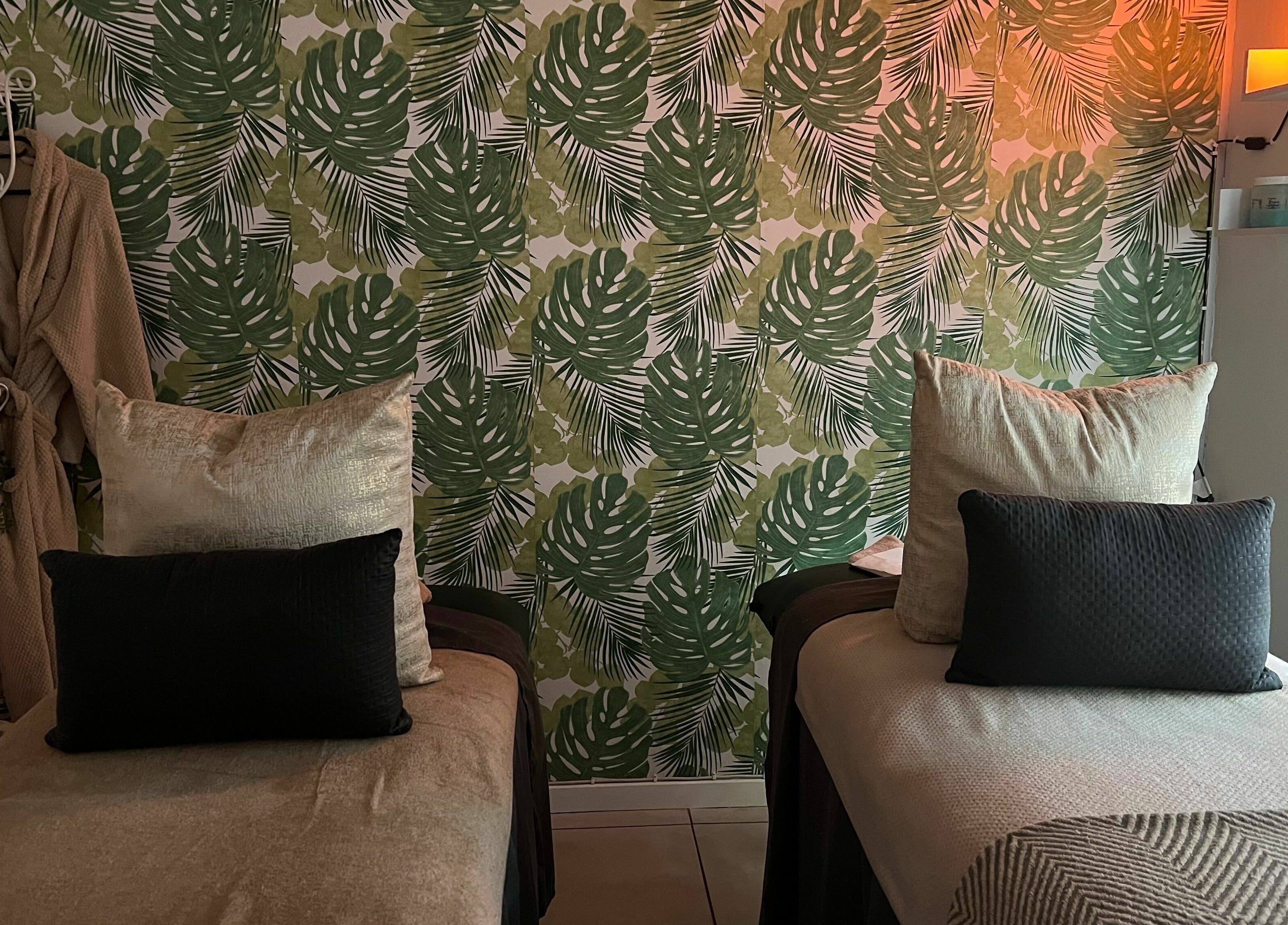Relaxing treatment room at Snes Wellness Space, Sandton, Gauteng, ZA with tropical leaf decor and cozy beds.