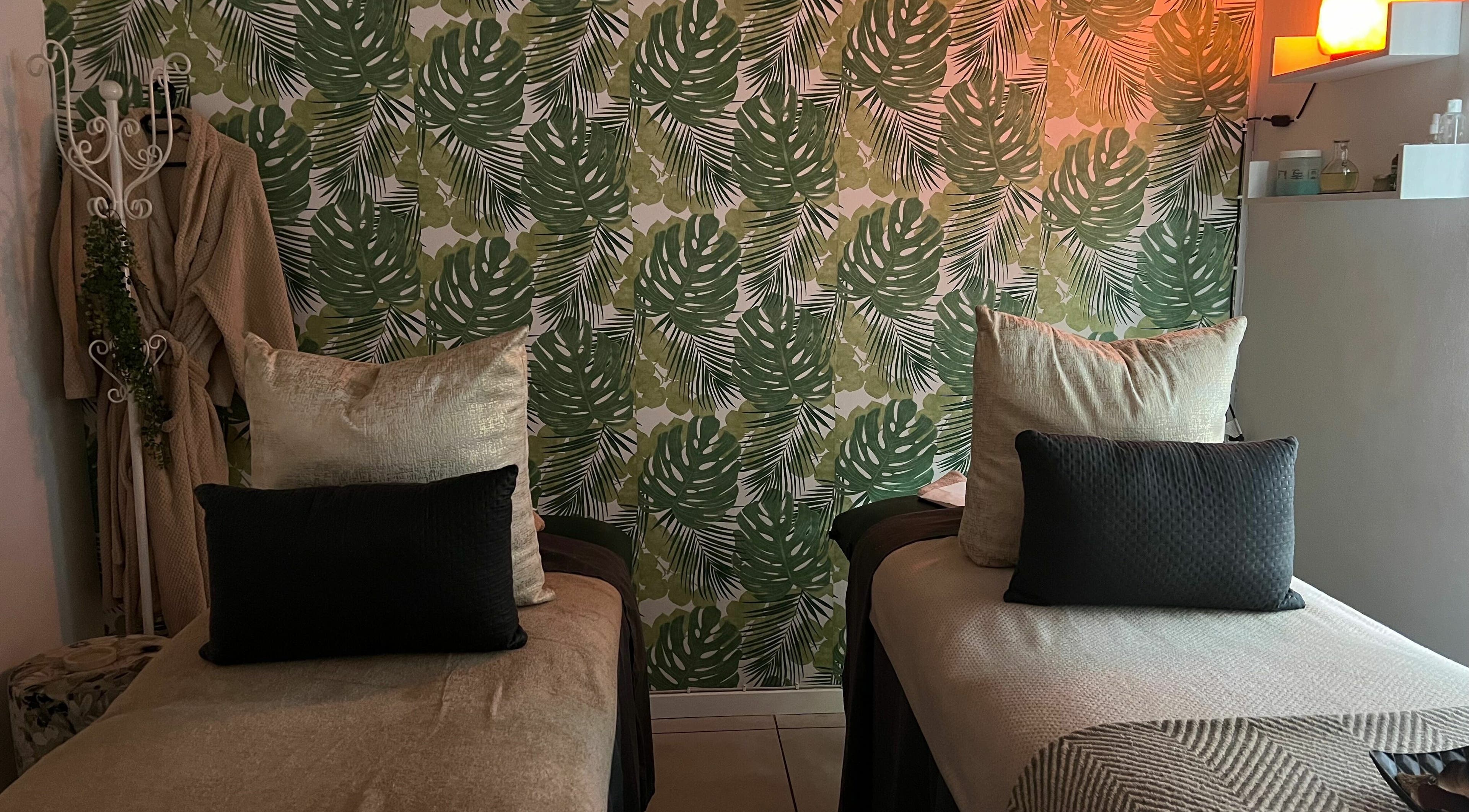 Relaxing treatment room at Snes Wellness Space, Sandton, Gauteng, ZA with tropical leaf decor and cozy beds.