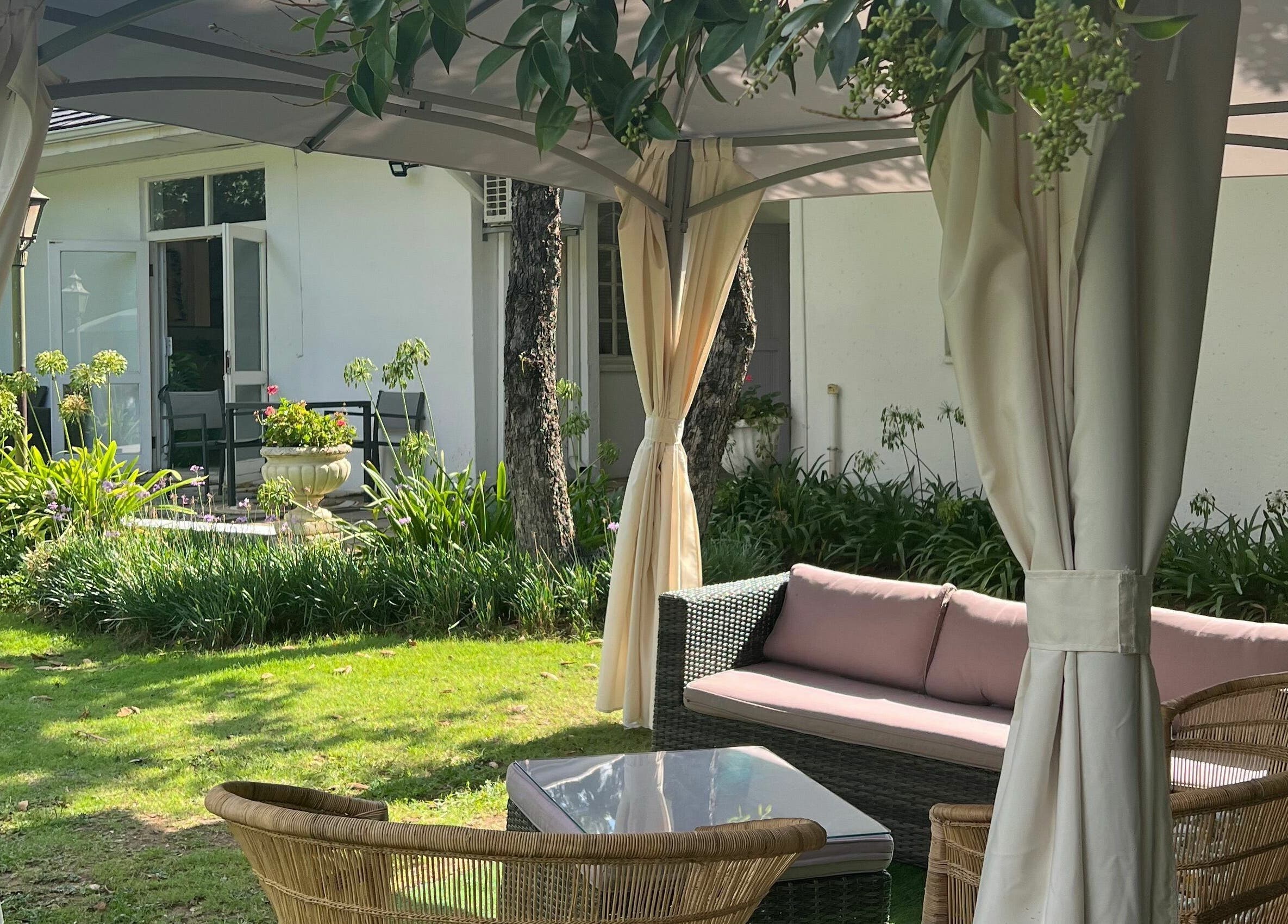 Outdoor seating area at Snes Wellness Space, Sandton, Gauteng, ZA featuring wicker chairs and lush garden.