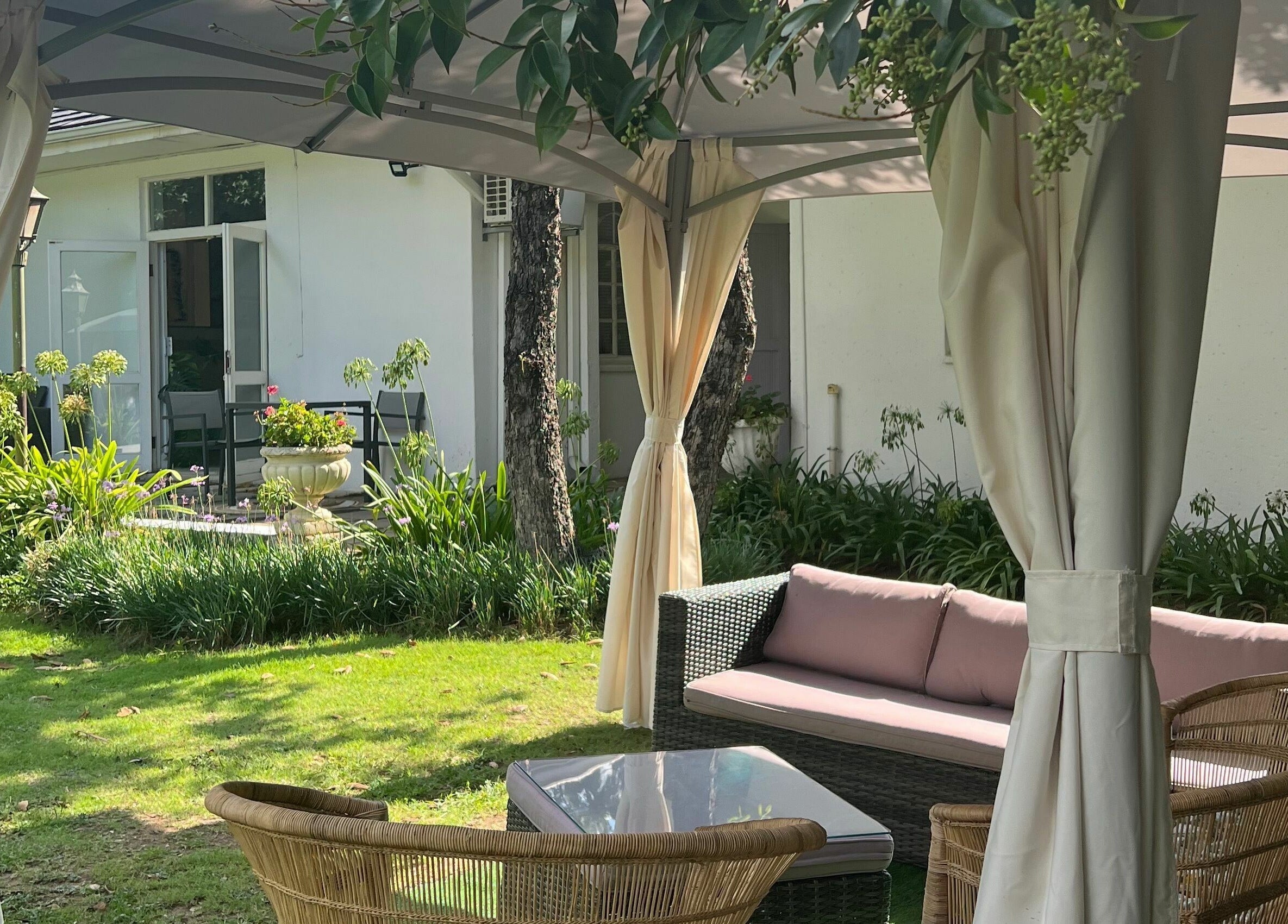 Outdoor seating area at Snes Wellness Space, Sandton, Gauteng, ZA featuring wicker chairs and lush garden.