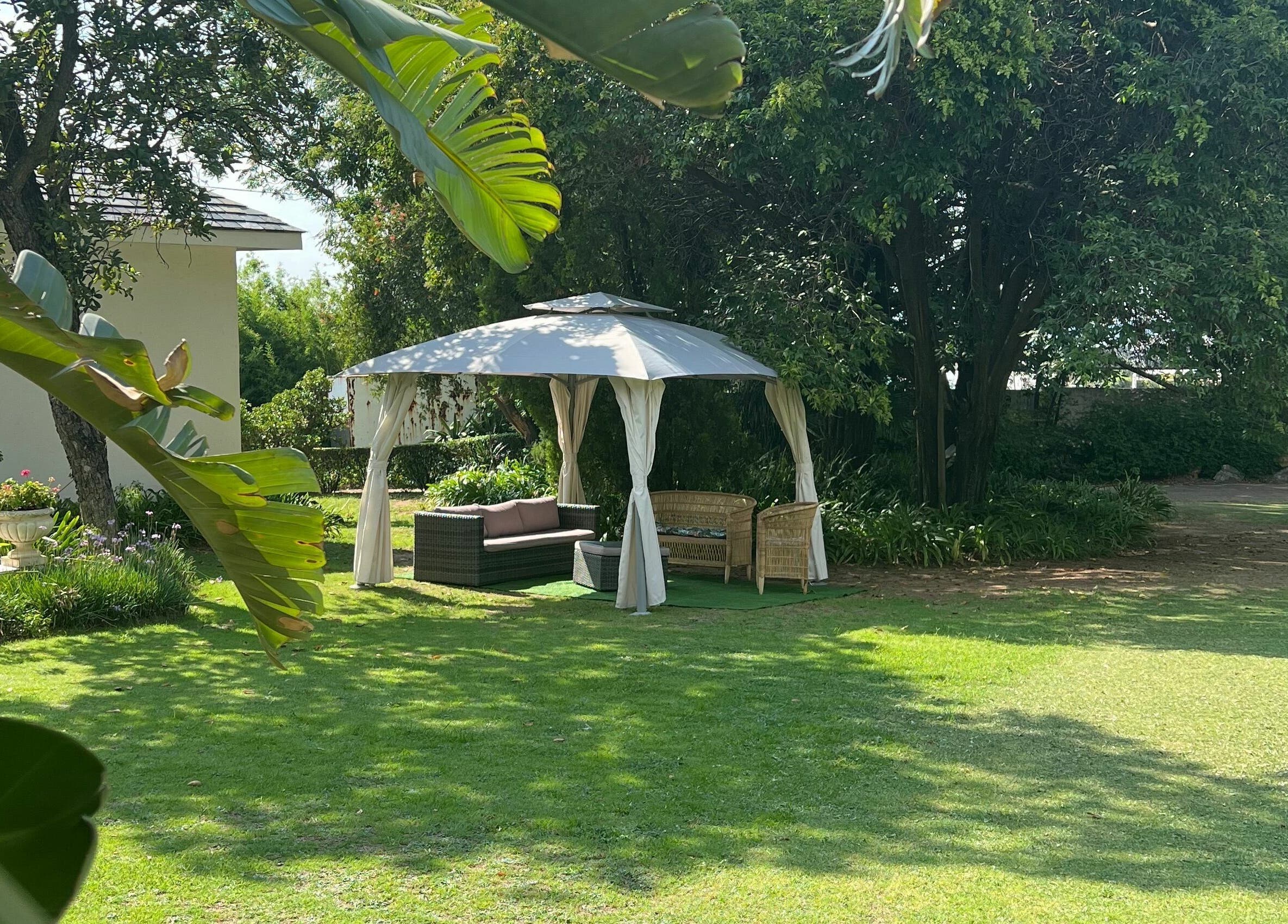 Serene outdoor gazebo at Snes Wellness Space, Sandton, Gauteng, ZA, surrounded by lush greenery and trees.