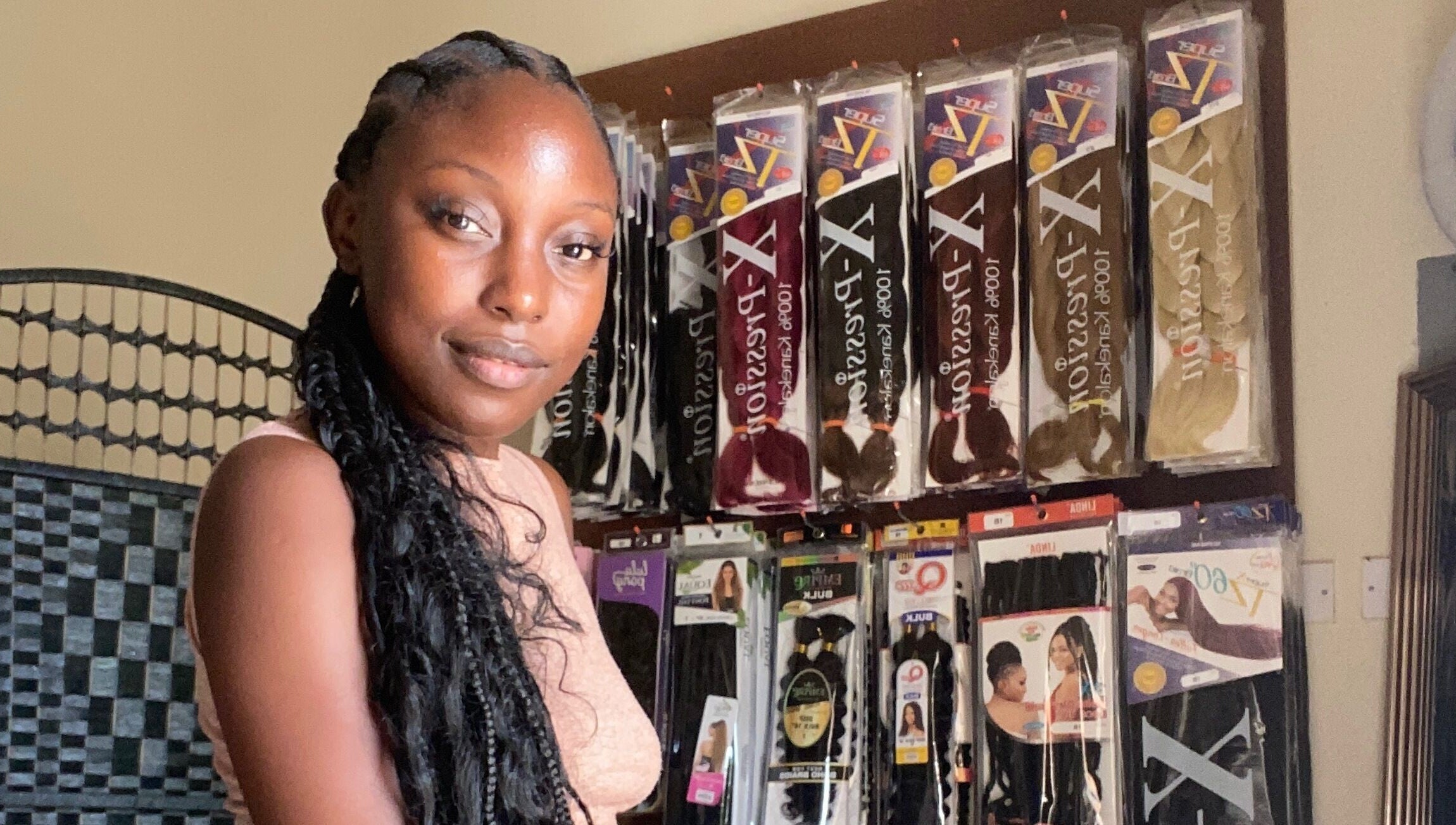 Woman with braids in front of hair products at Fro and Glo Beauty in Bridgetown, Saint Michael, BB.