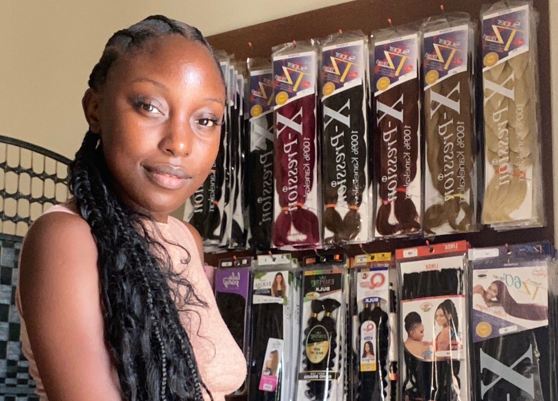 Woman with braids in front of hair products at Fro and Glo Beauty in Bridgetown, Saint Michael, BB.