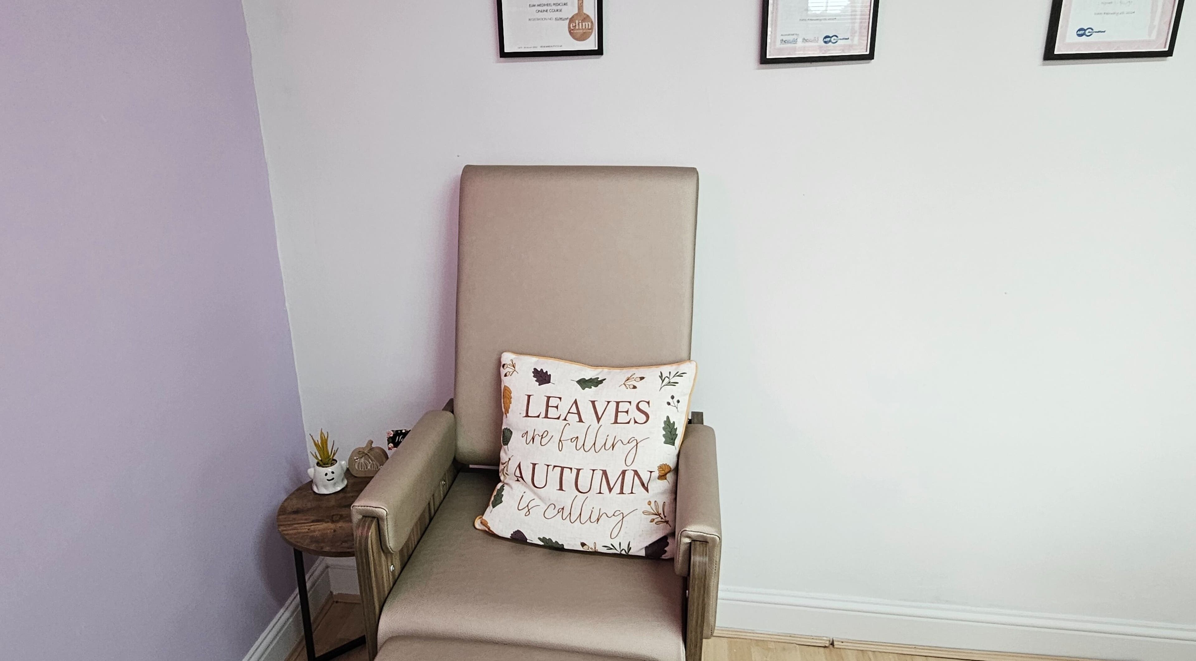 A comfy chair with an autumn-themed pillow at Nails by Verity, Tenterden, England, GB.