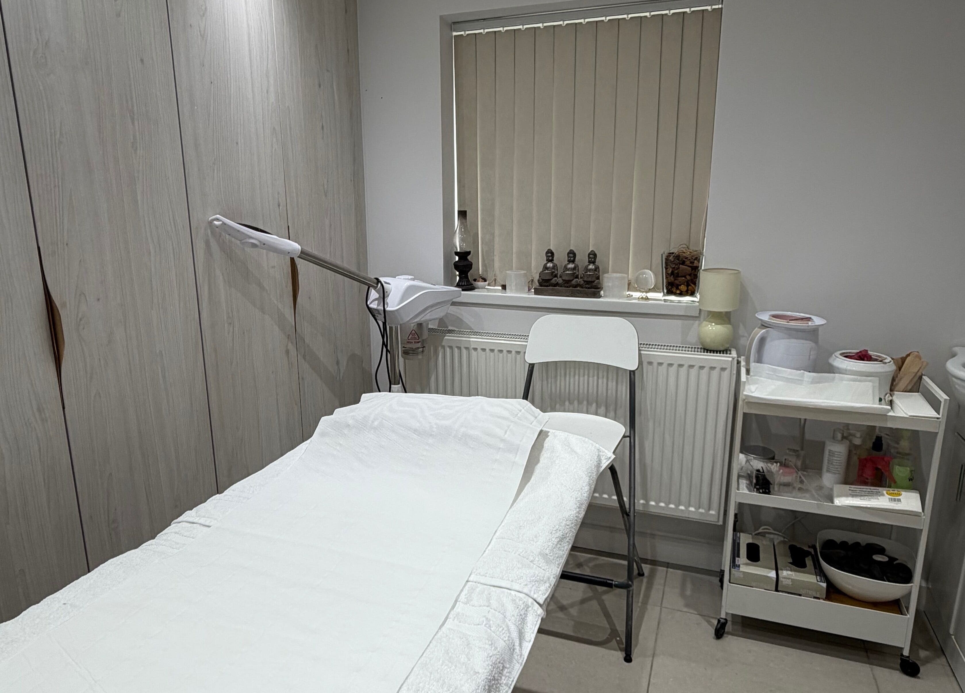 Cozy treatment room at Kay in Hounslow, England, GB, featuring a massage table and calming decor.