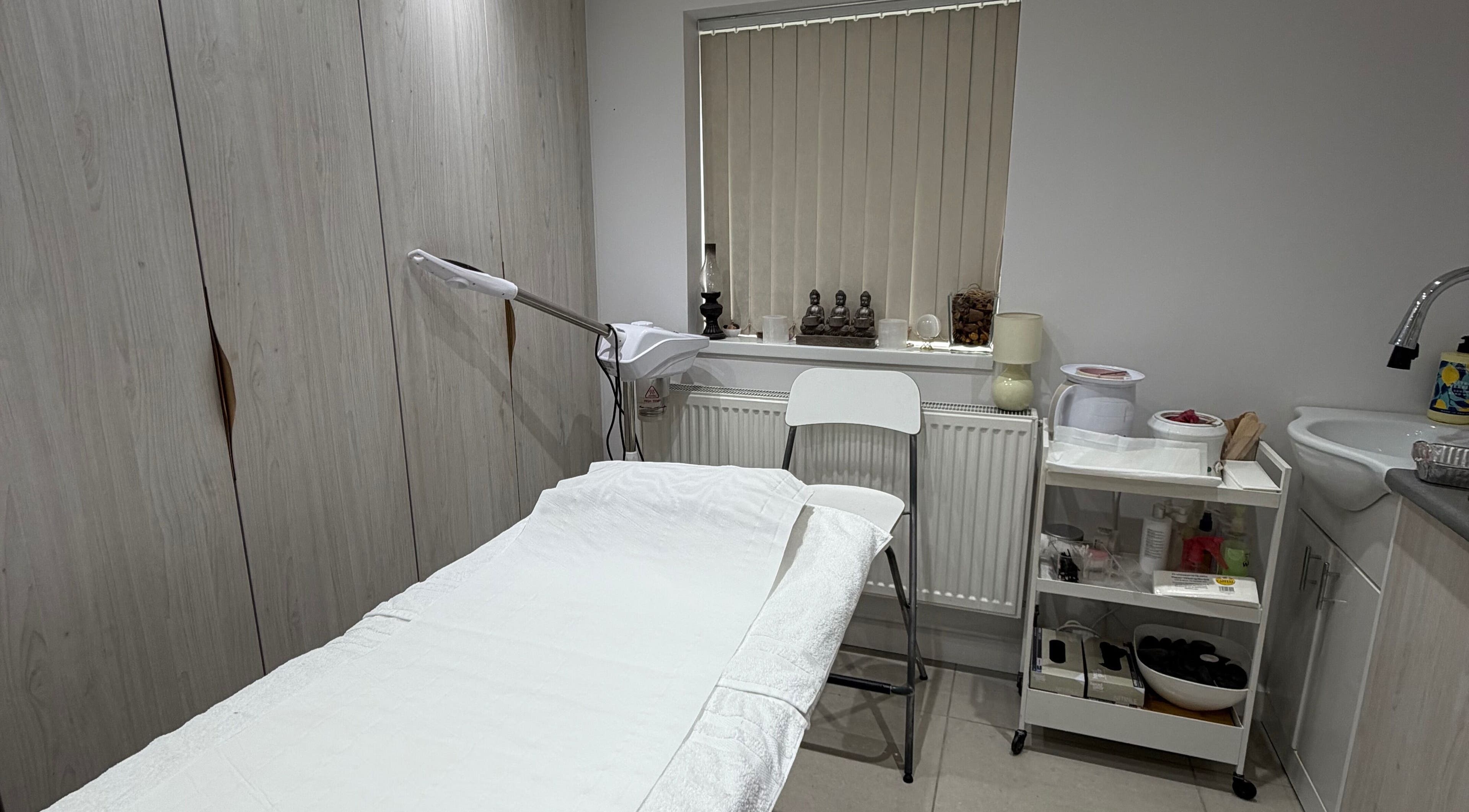 Cozy treatment room at Kay in Hounslow, England, GB, featuring a massage table and calming decor.