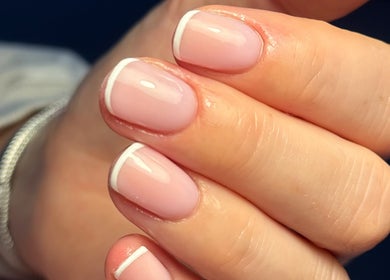 Close-up of a French manicure at MCR Beauty Room, Worsley, England, GB showcasing neat pink polish and white tips.