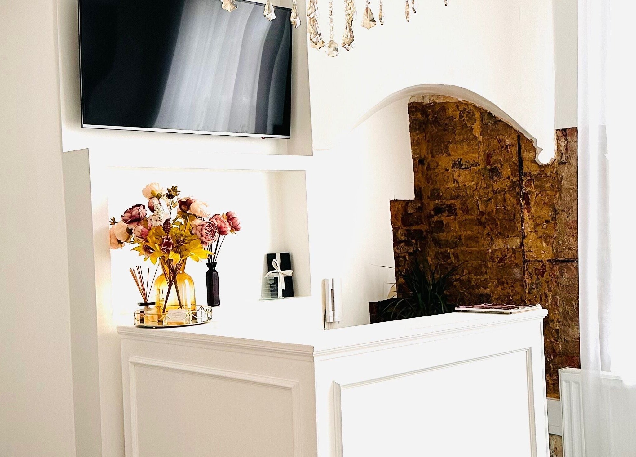 Reception area at MK Aesthetics Clinic in Derby, England, featuring a white desk and floral decor.