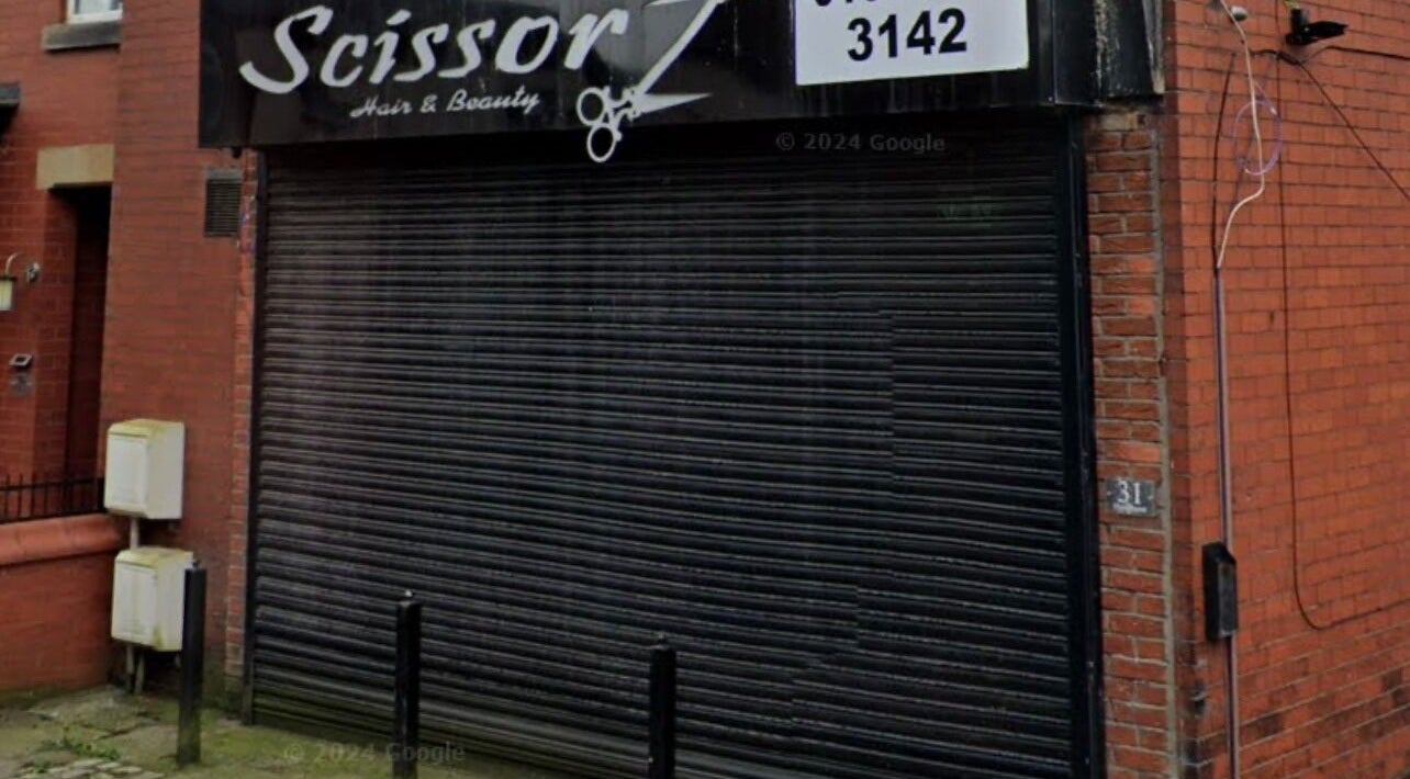 Street view of BARE FACED beauty venue in Worsley, England with closed metal shutters.