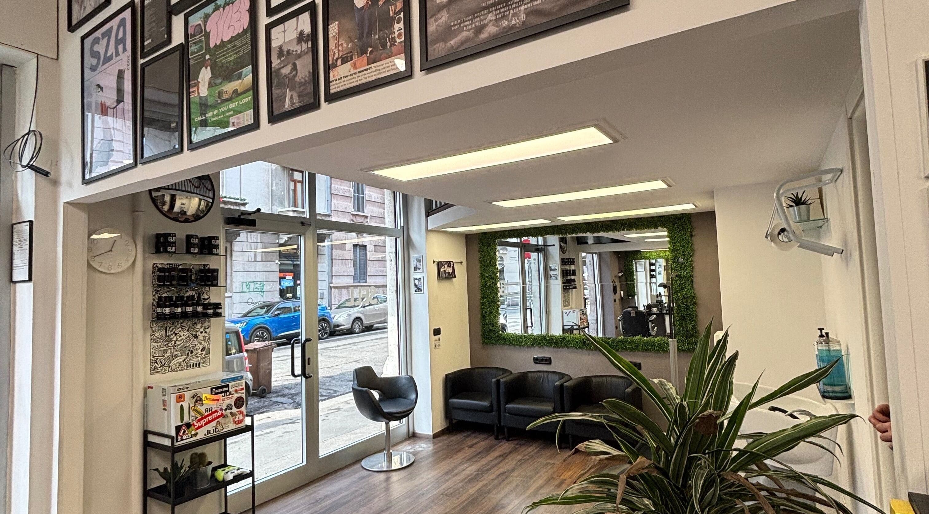 Interno moderno di Sell Barbers, Milano, Lombardia, IT con sedie eleganti e specchi verdi.